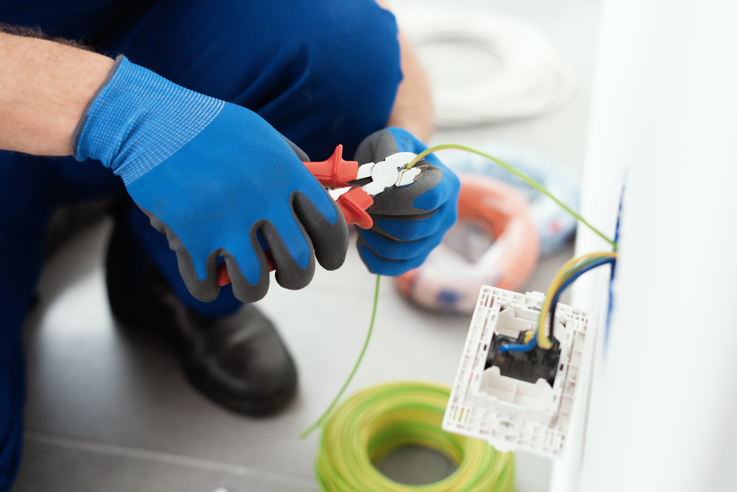 A person wearing blue gloves working with electrical wires and a circuit board.