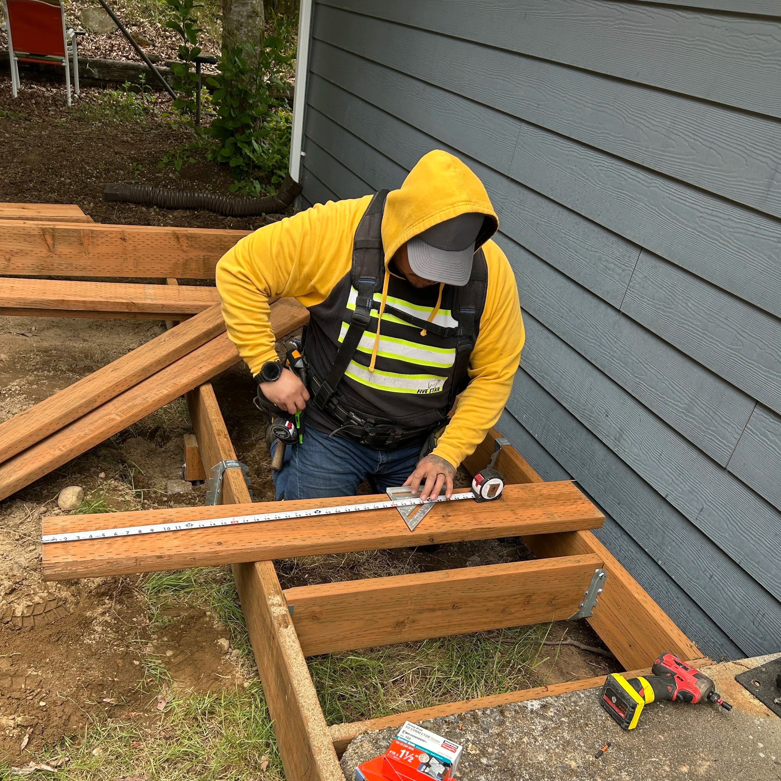 worker measuring lumber for deck