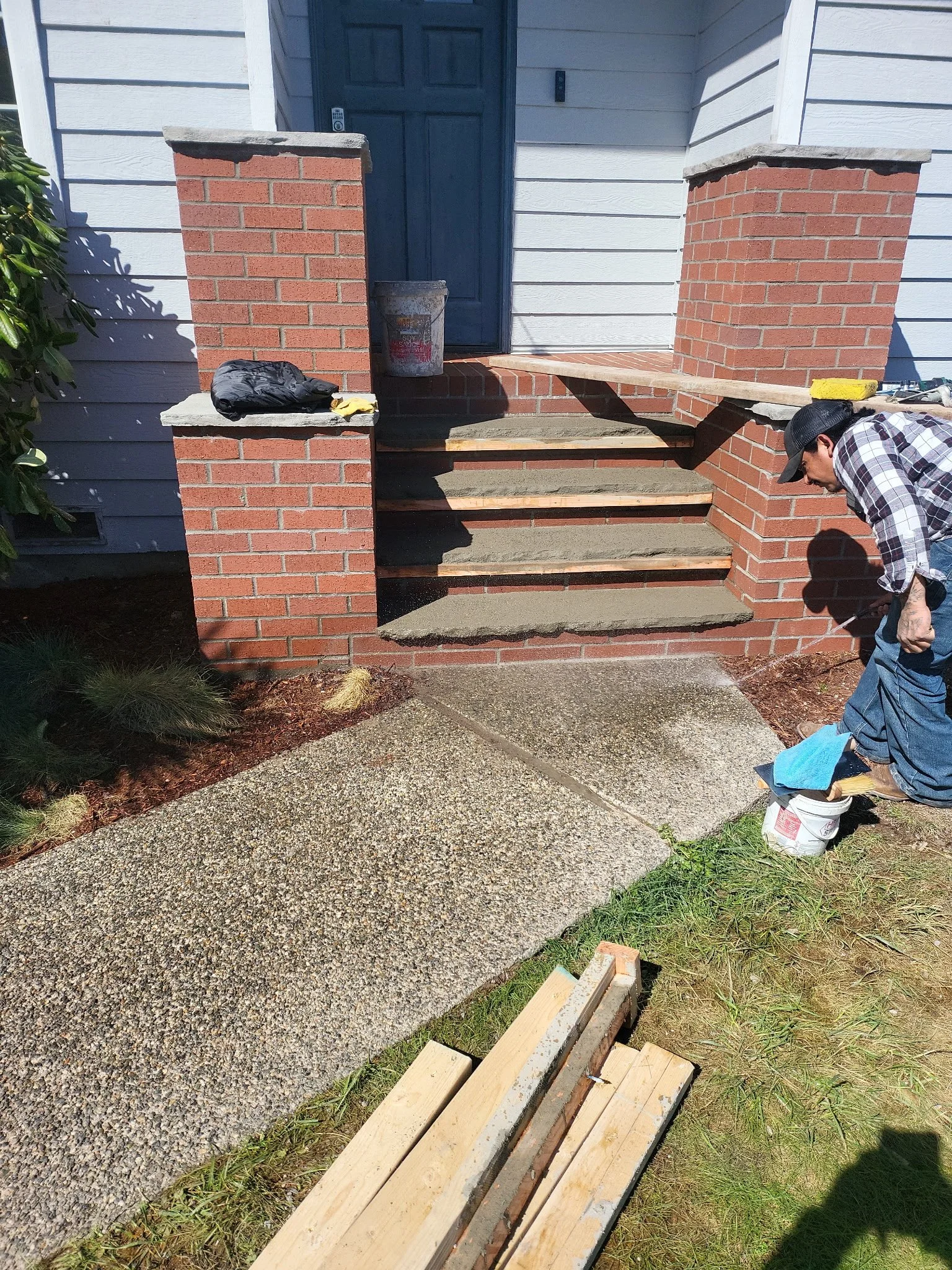 Brick stairs into house, man power-washing walkway