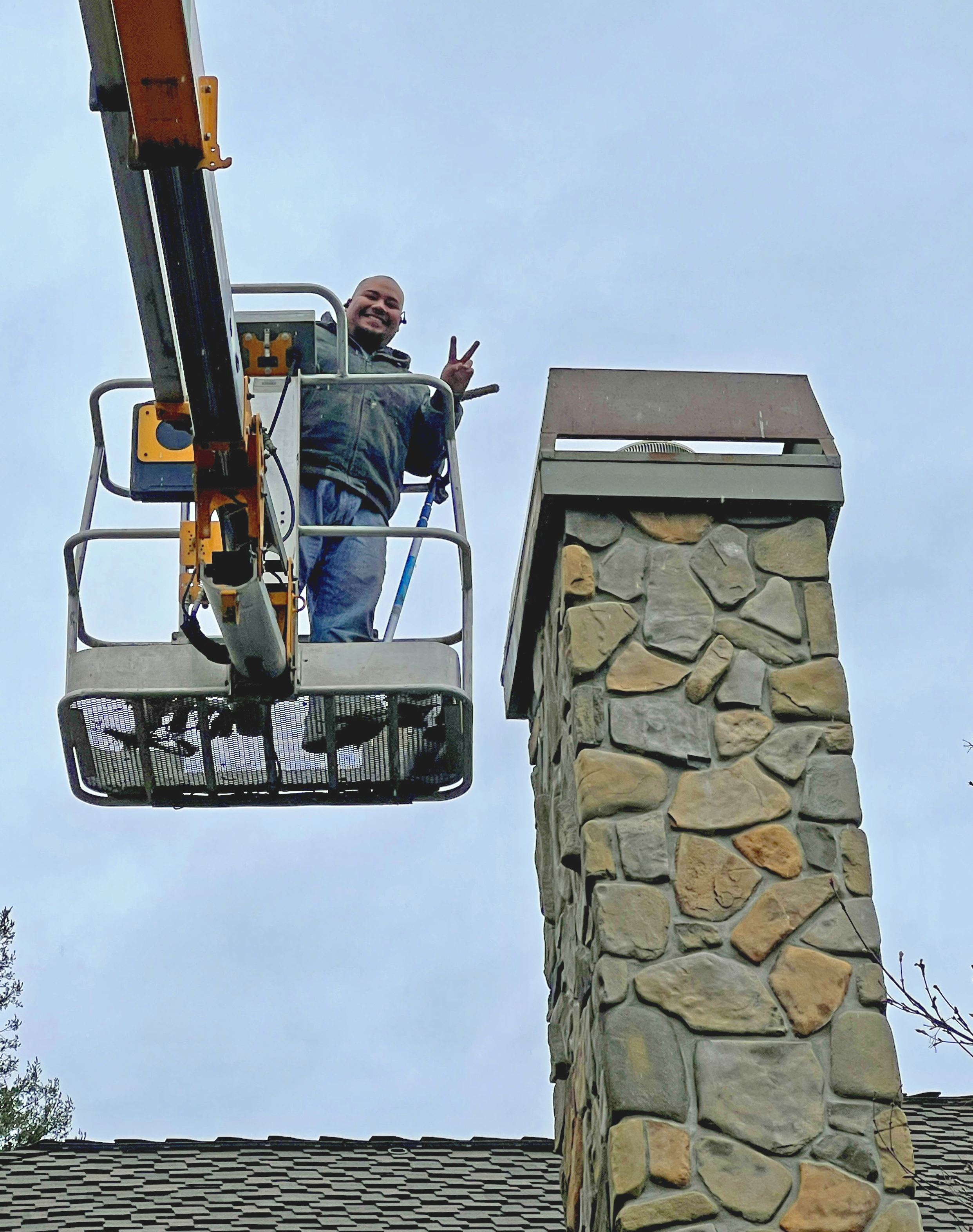 Javier in an articulated lift fixing a chimney and smiling for the camera
