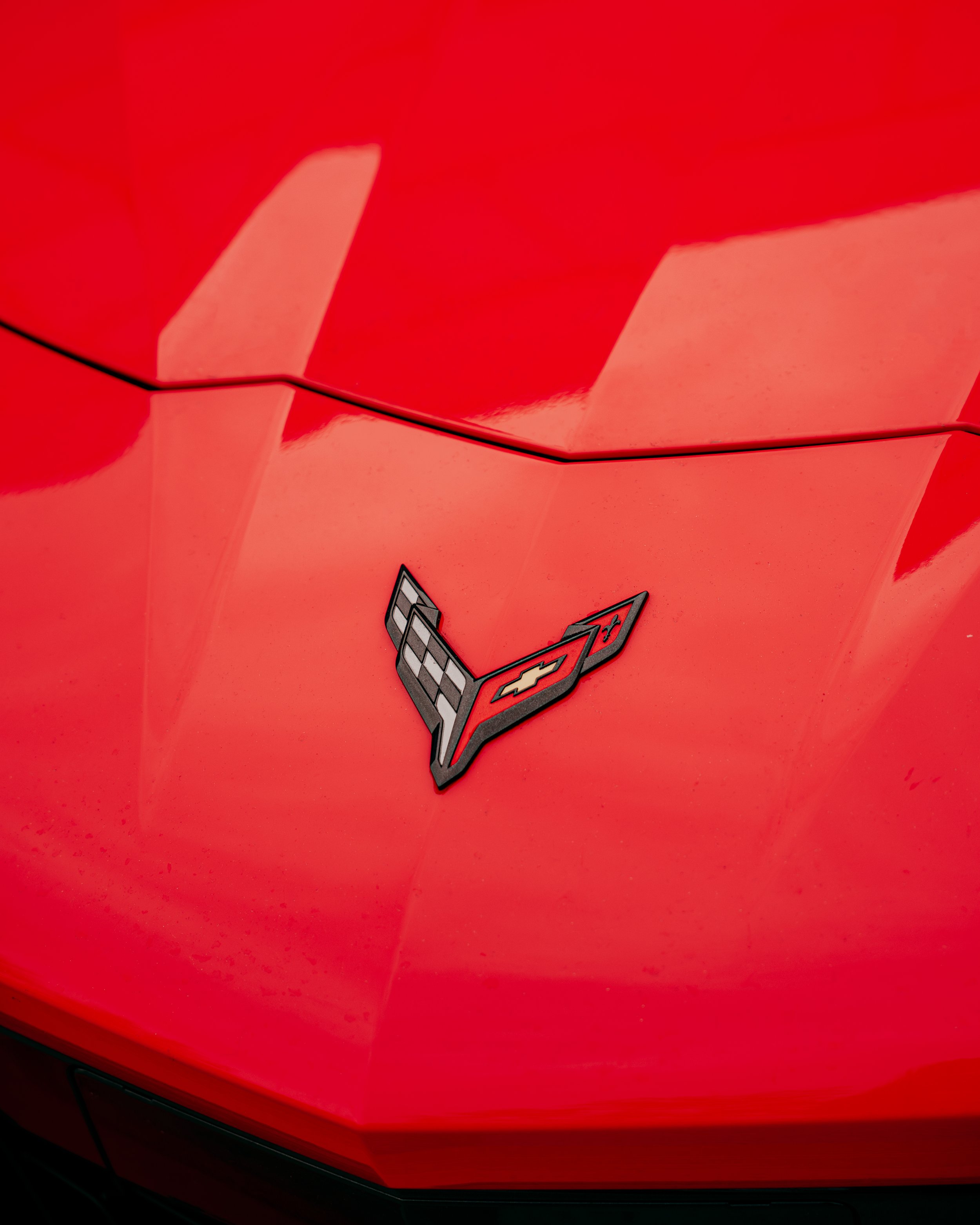 Close-up of a red Chevrolet Corvette car with Corvette emblem on the hood.
