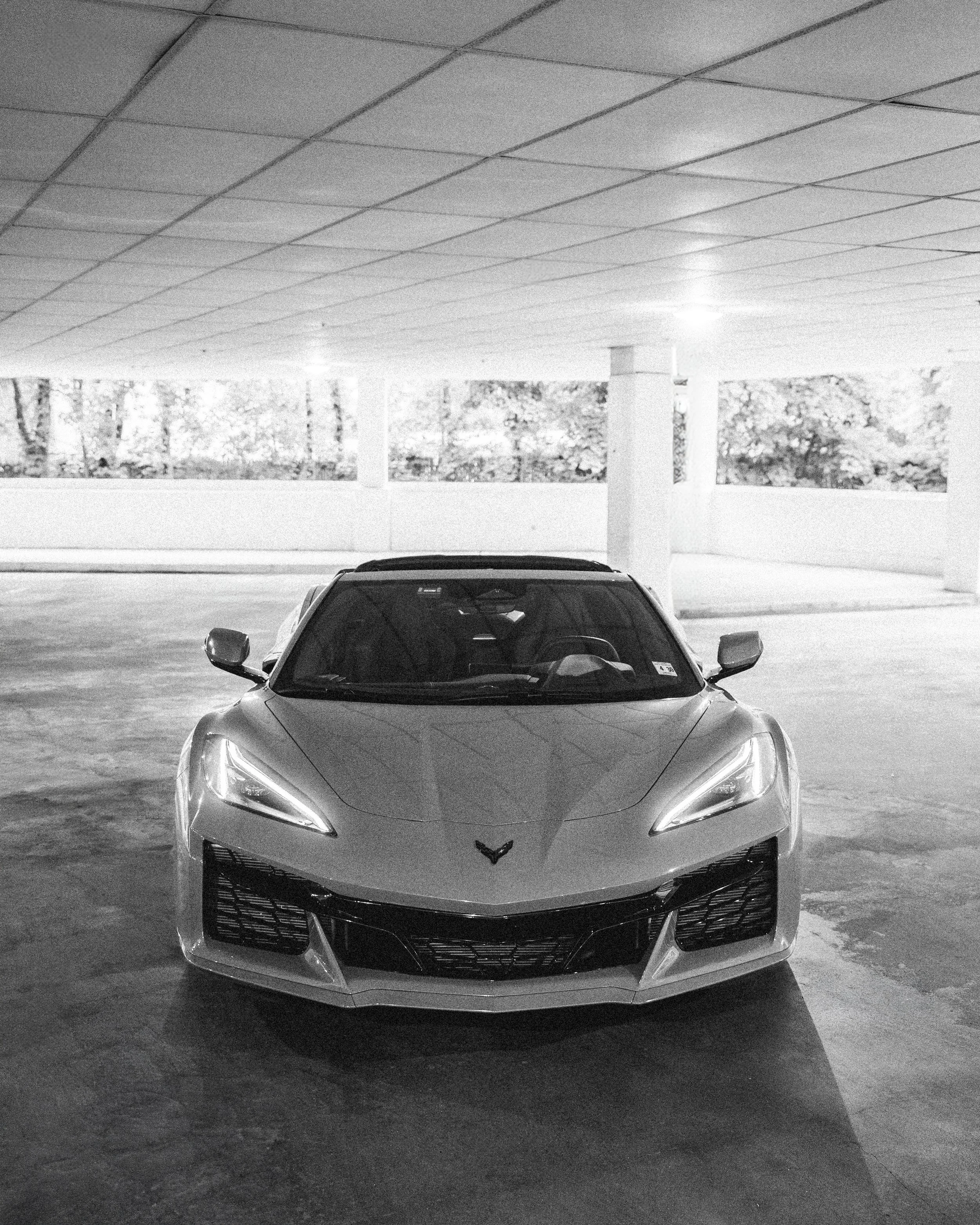 Front view of a gray sports car parked in an indoor parking garage.