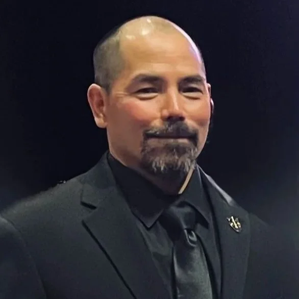Headshot of smiling male tutor with medium-length black hair wearing a lanyard.