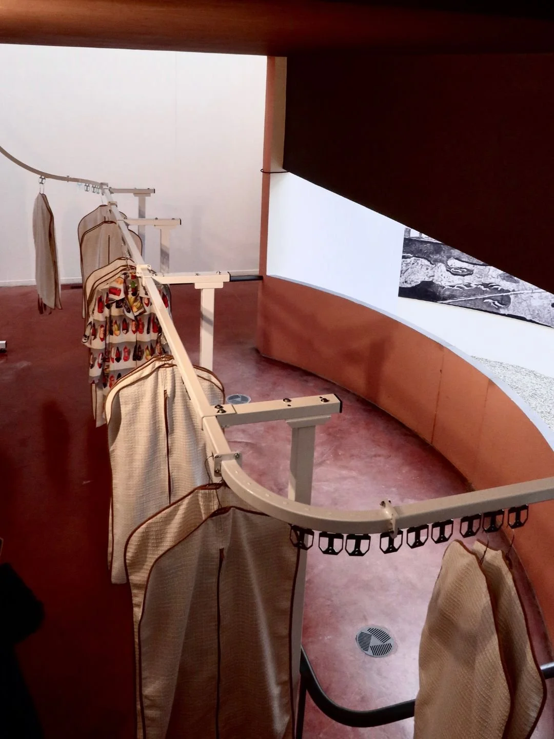 L'interno di un museo con una parete curva e un proiettore che mostra un'immagine in bianco e nero di un paesaggio o mappa.