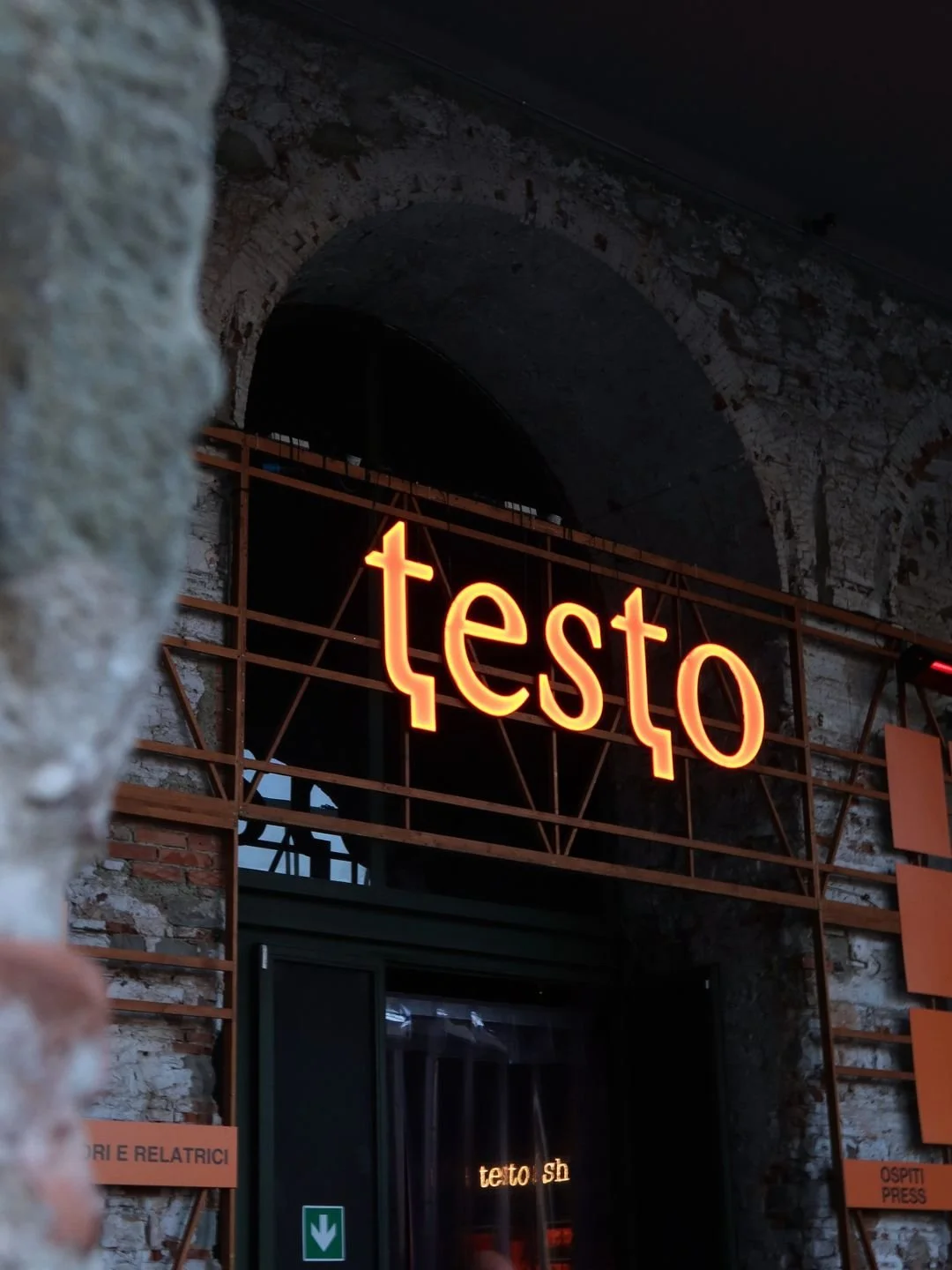 Reportage fotografico d'atmosfera a Firenze: dettaglio dell'insegna luminosa arancione dell'evento editoriale Testo alla Stazione Leopolda.