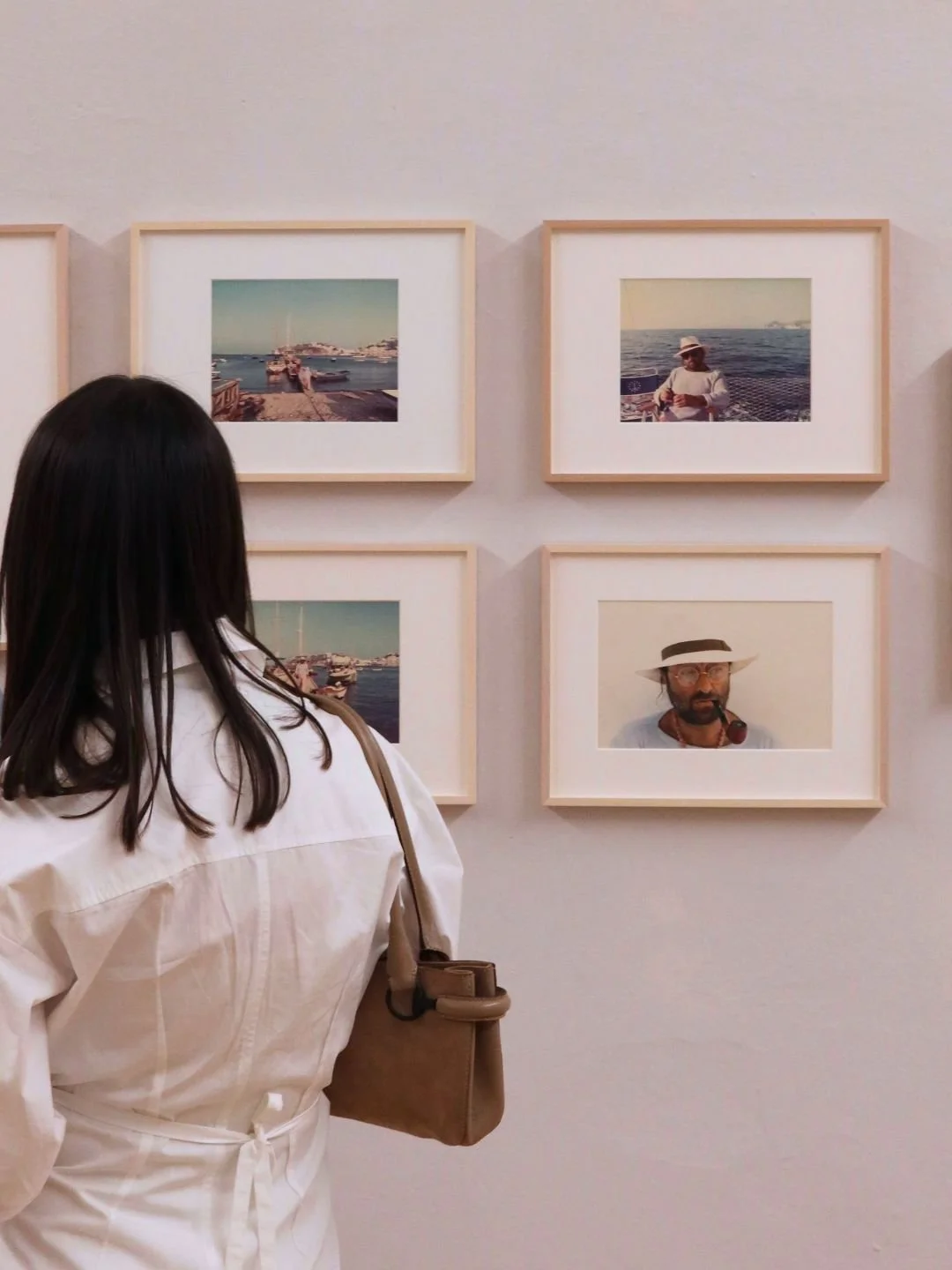 Una visitatrice osserva le celebri fotografie di paesaggi e marine di Luigi Ghirri a Reggio Emilia. Narrazione live e memoria visiva di mostre d'arte contemporanea.