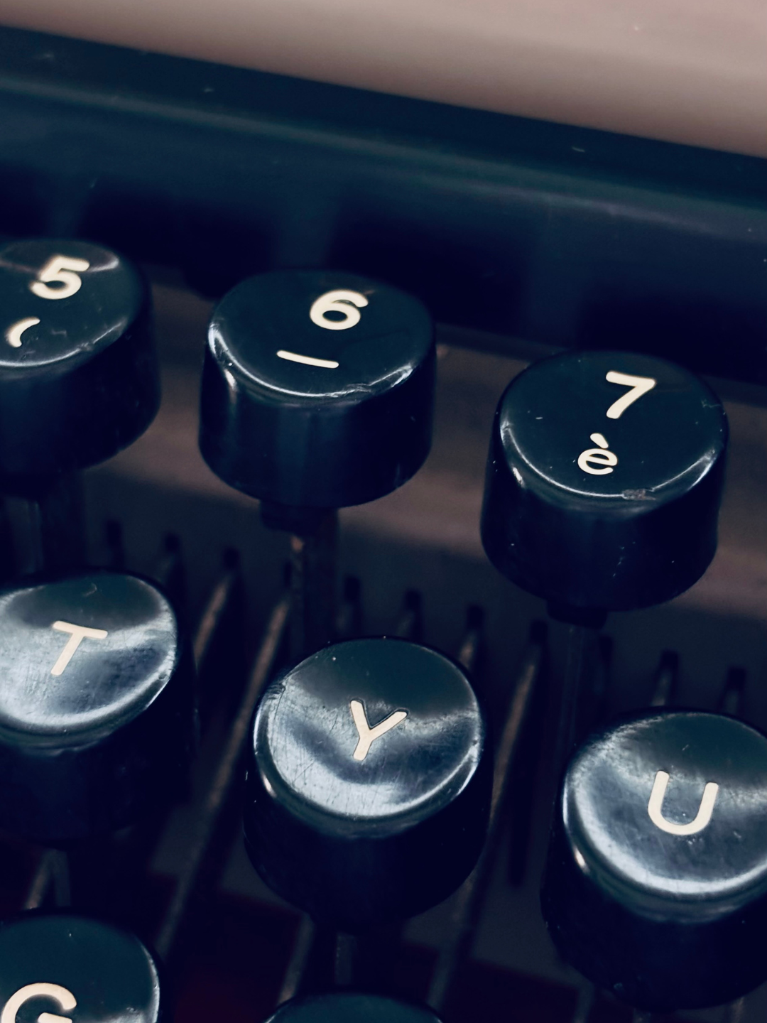 Tastiera di una macchina da scrivere con tasti neri e caratteri bianchi, evidenziando i tasti con i numeri 5, 6 e 7 e alcune lettere come Y, U, T.