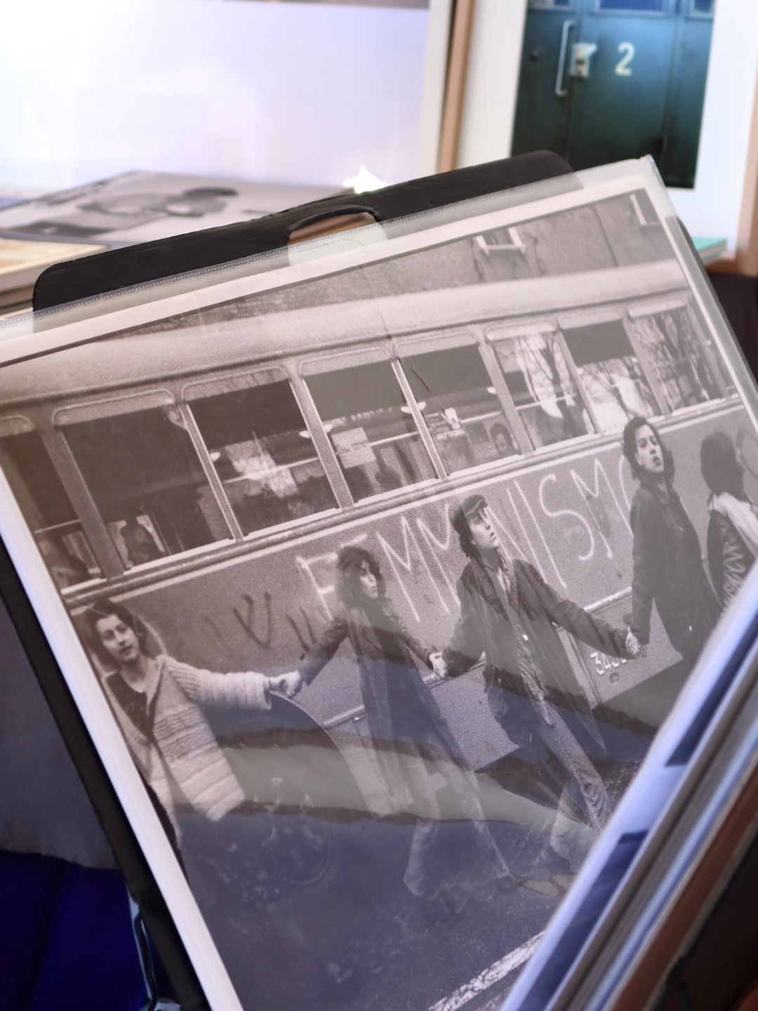 Foto in bianco e nero di quattro persone che attraversano una strada tenendosi per mano davanti a un pullman con scritte sulla fiancata.