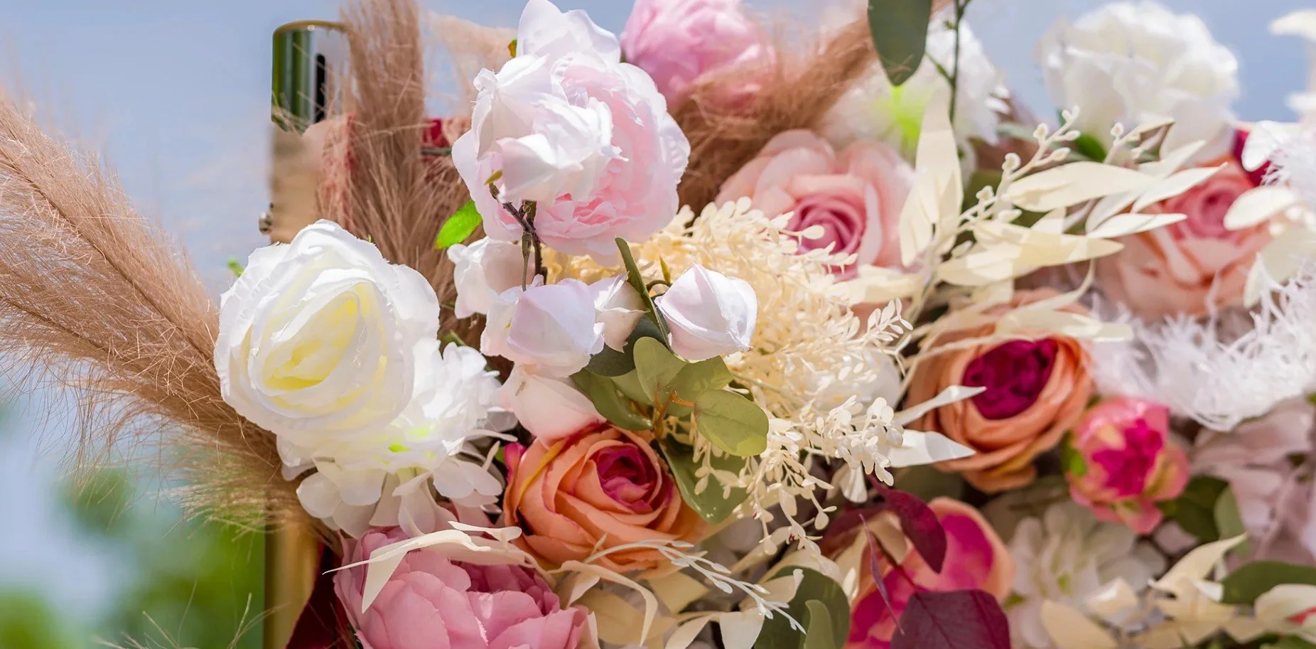 Close-up of a colorful flower bouquet with roses, peonies, and greenery, arranged in a rustic style.