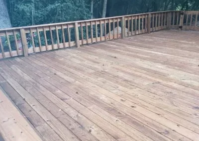Wooden deck with a railing overlooking a wooded area.