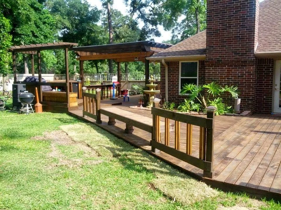 Backyard with a wooden deck, a gazebo, and green trees.