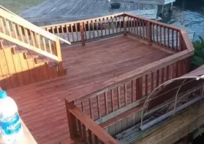Wooden deck with railings and stairs leading down to water's edge.
