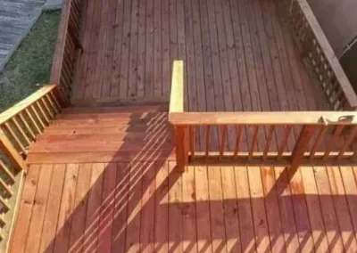 A wooden deck with railings, showing a section being reconstructed with new wood panels.