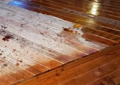 A wet wooden floor with water and dirt stains.
