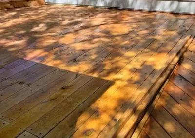 Close-up of a wooden deck with some planks lighter in color and shadowed areas.