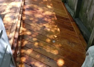 Wooden deck with sunlight and shadow patterns from nearby trees.