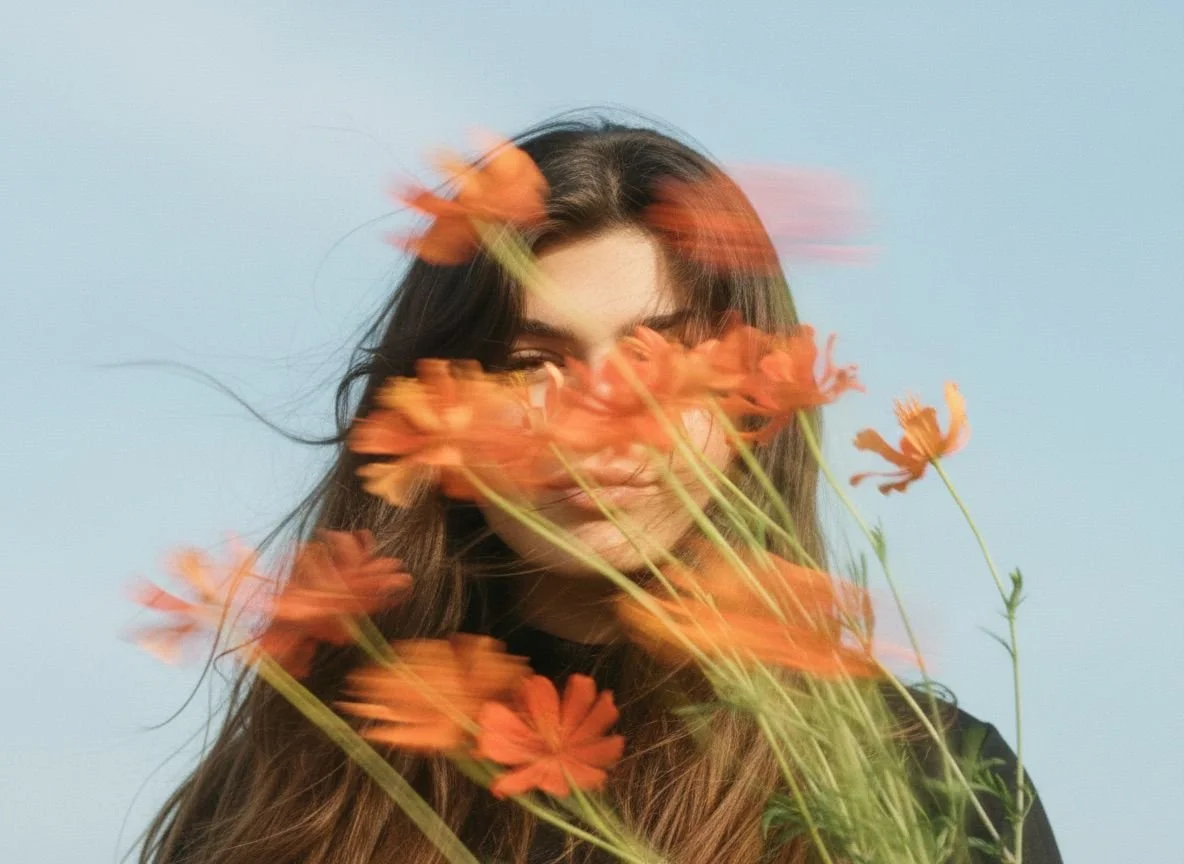 woman with long dark hair and orange flowers 
obscuring her face, editorial portrait for 
Storytotellers creative consultancy
