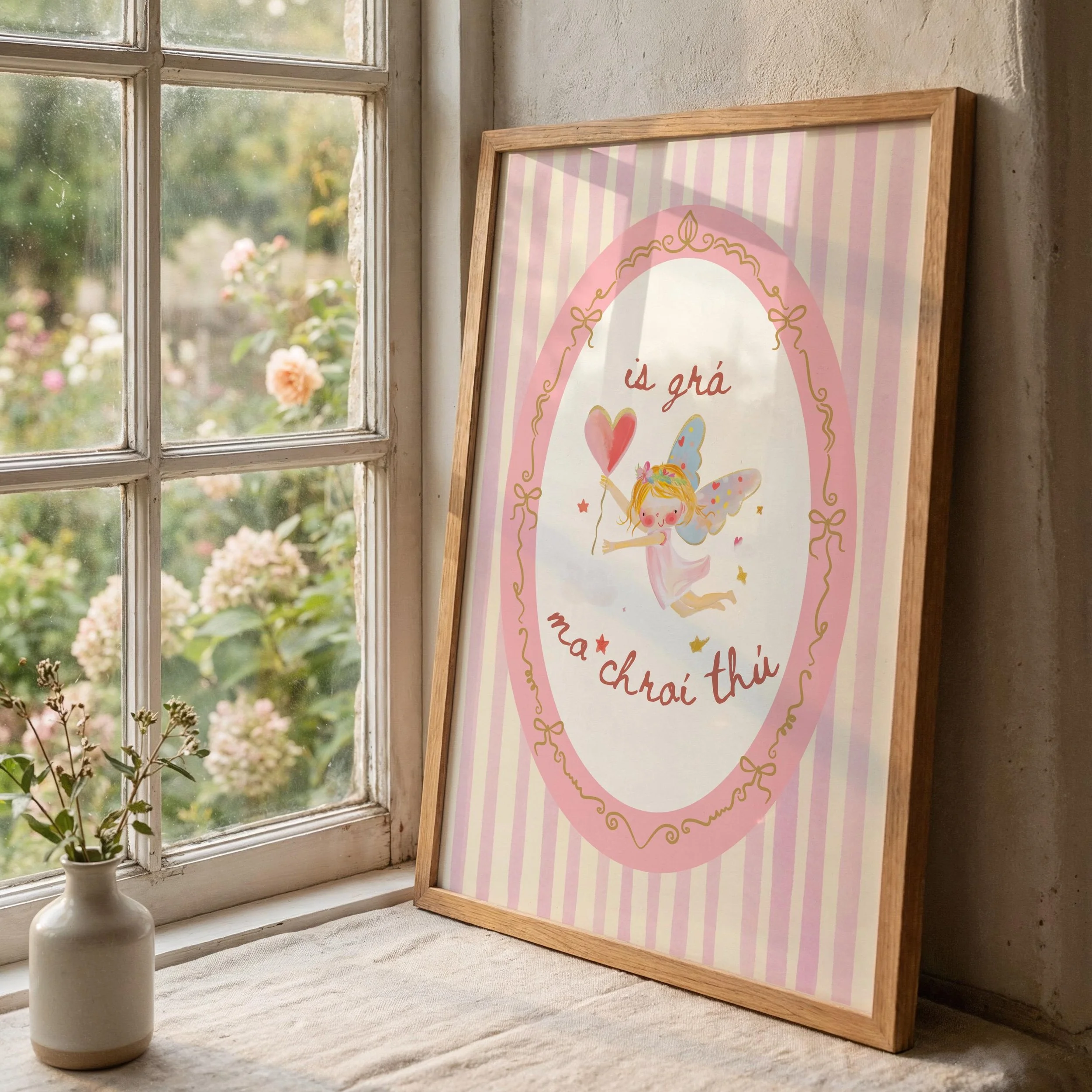 A framed pink and white striped poster with a fairy illustration, placed on a windowsill next to a white vase with small plants, with a garden outside.