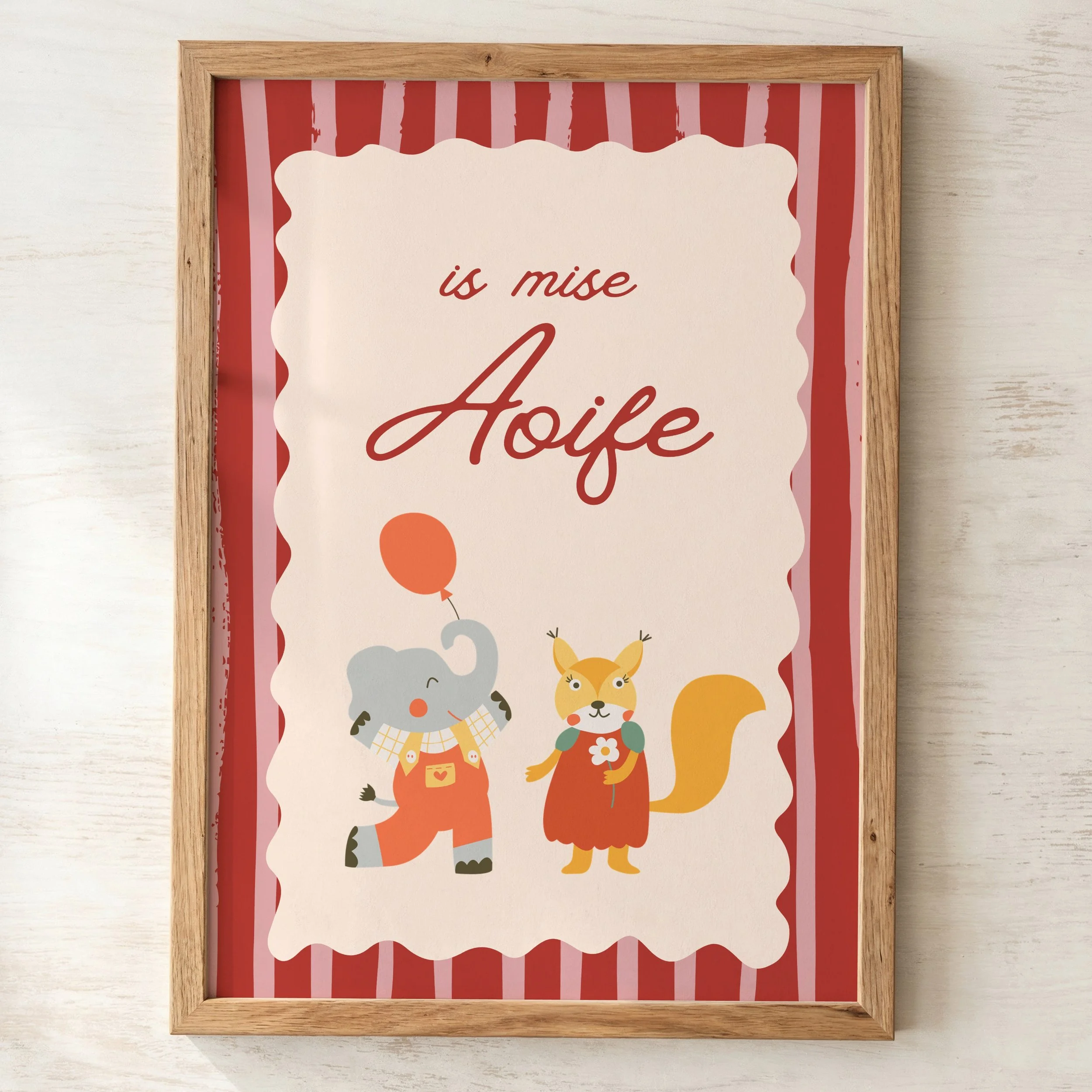 Decorative framed sign with a wooden border, featuring a red and pink vertical striped pattern and playful illustrations of animals, including a dog and a cat, with partially visible text in red cursive that reads 'is mise' and 'A'.
