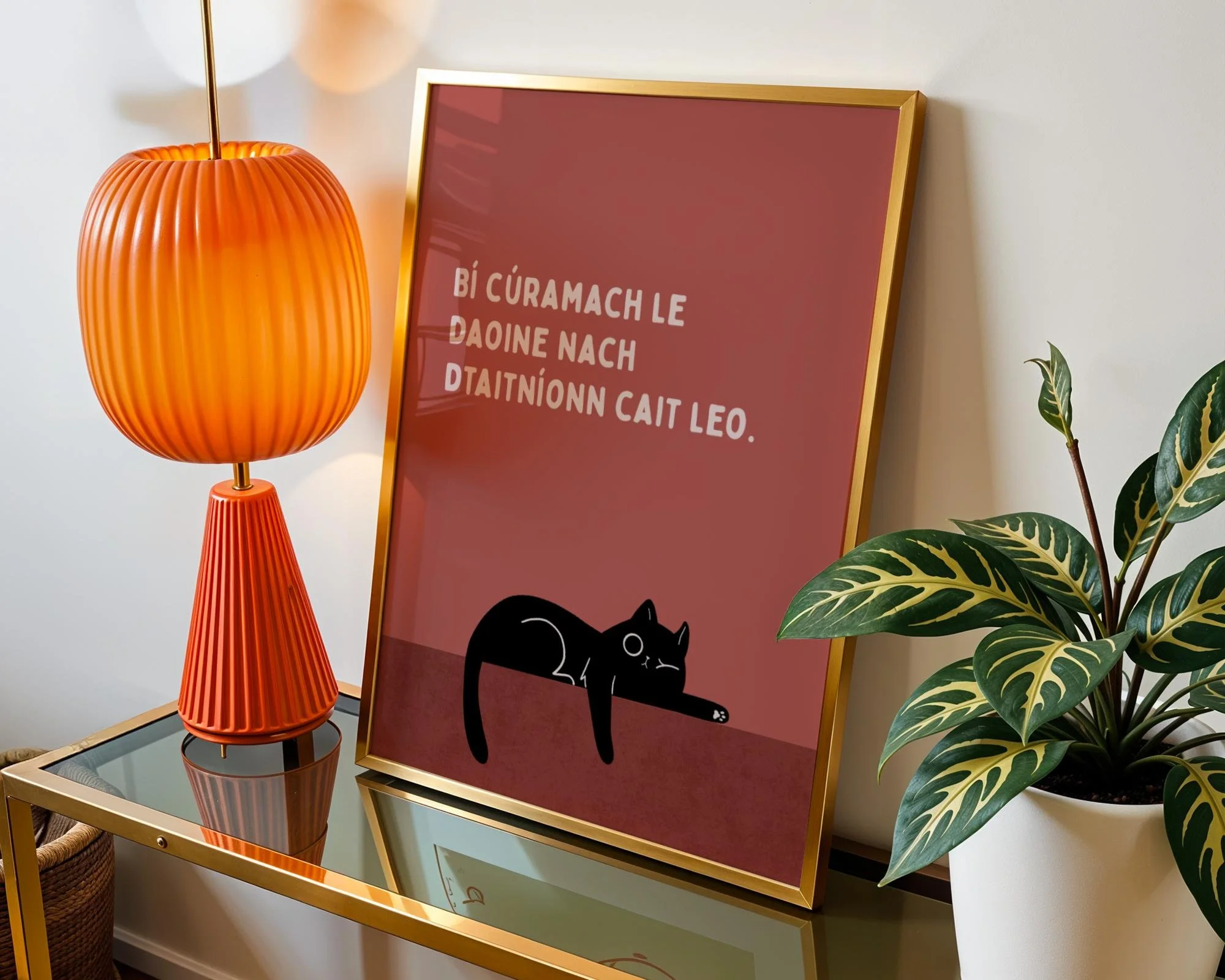 A decorated wall with a tall orange lamp, a framed pink print with white text and a black cat illustration, a glass shelf, and a potted plant with green and yellow leaves. Irish seanfhocal / proverb about cats