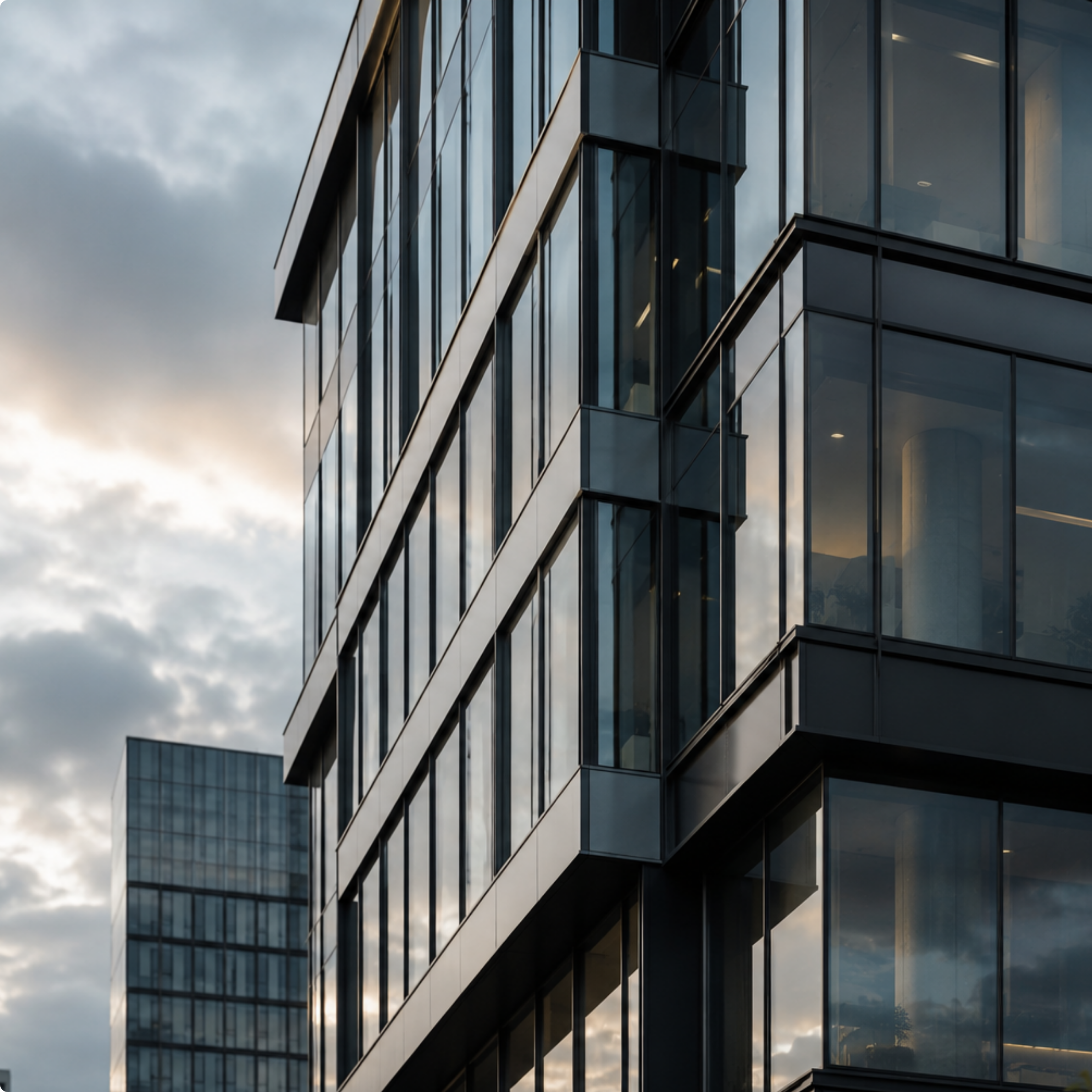 Close-up of a modern glass building with reflections of the cloudy sky.