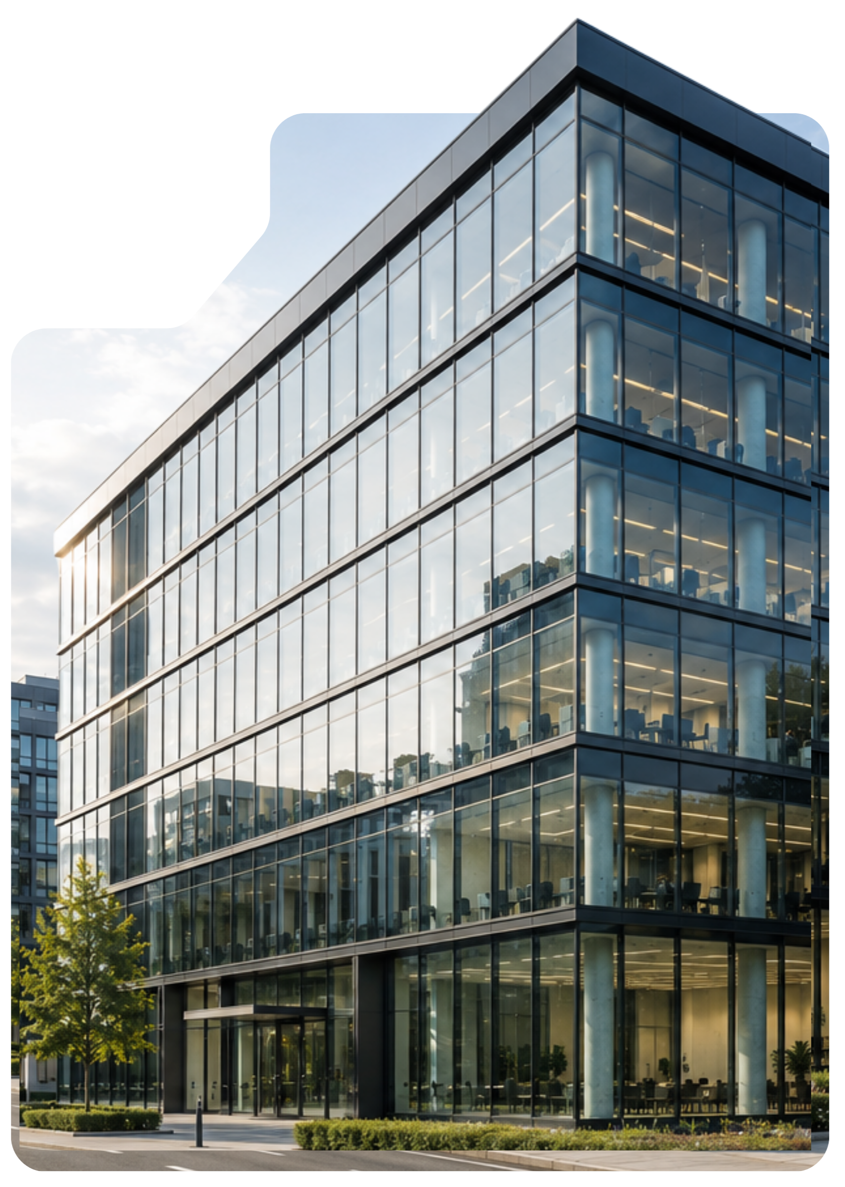 Modern multi-story office building with large glass windows, a sidewalk, trees, and street lamps, under a partly cloudy sky.