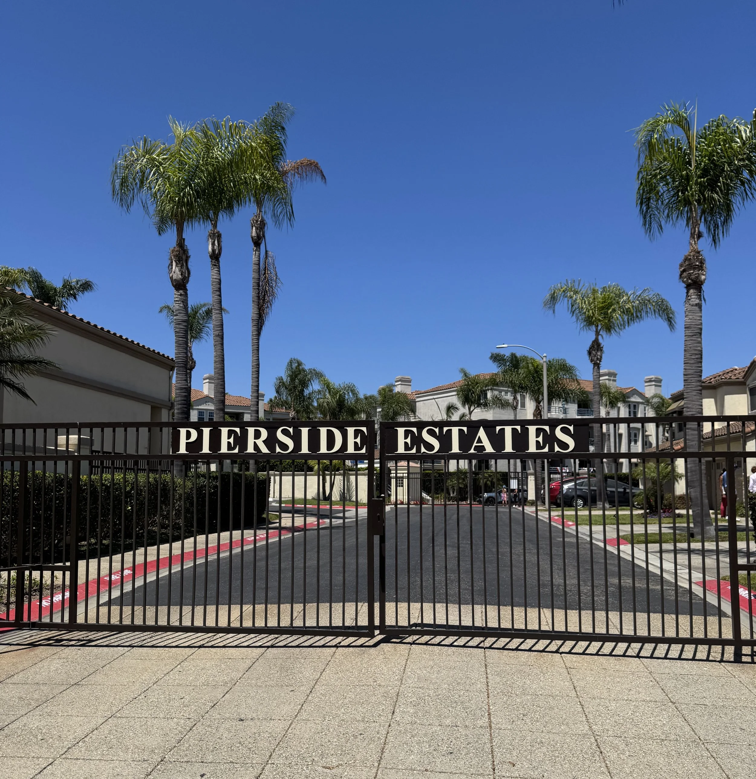 Pierside Estates townhomes for sale in Huntington Beach featuring the community gates with name placard.