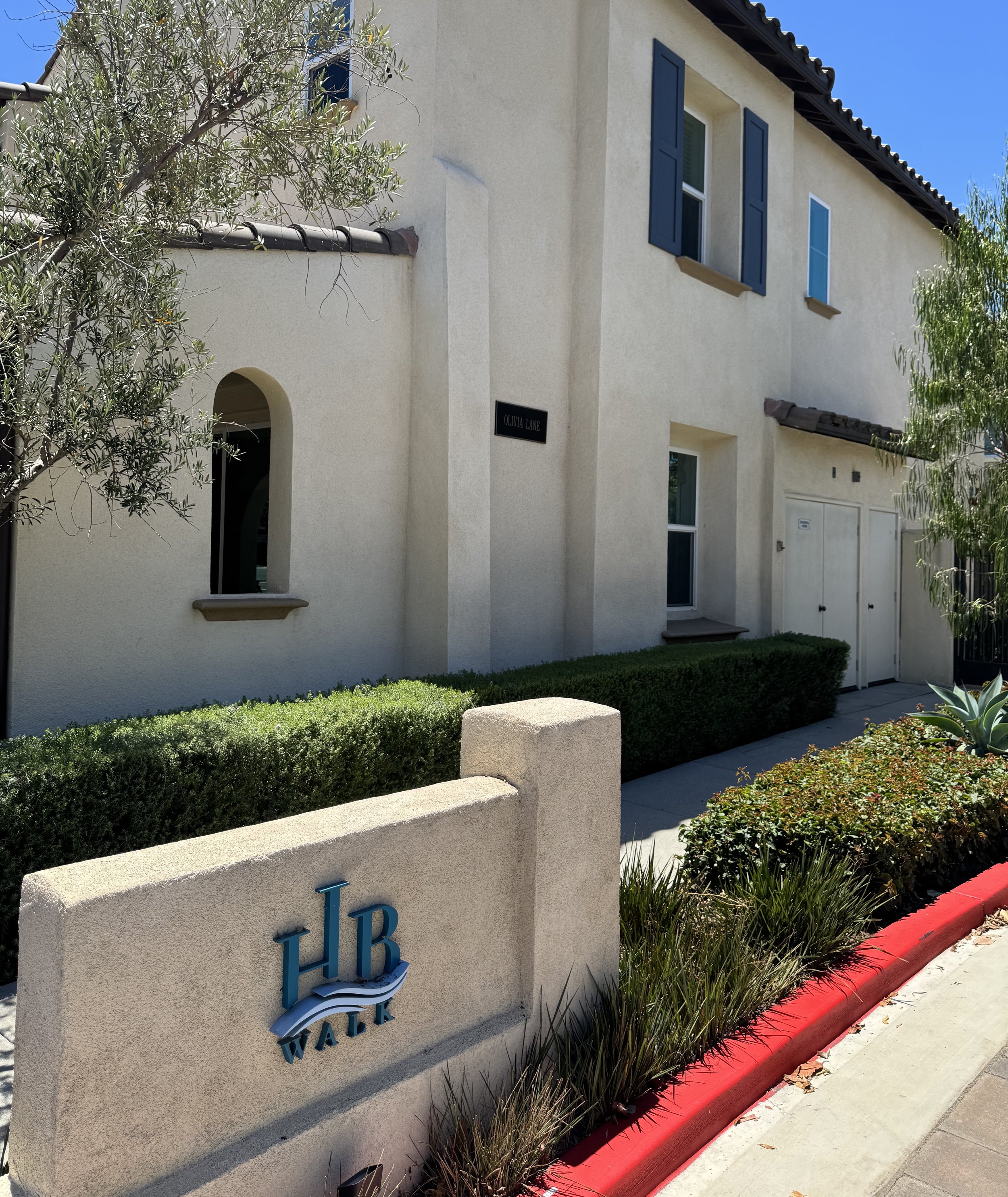 HB Walk townhomes for sale in Huntington Beach featuring the community entrance sign placard.