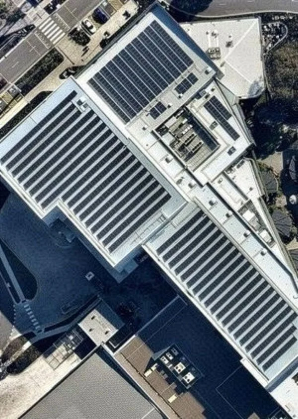 Aerial view of a large building with multiple solar panels on the roof.