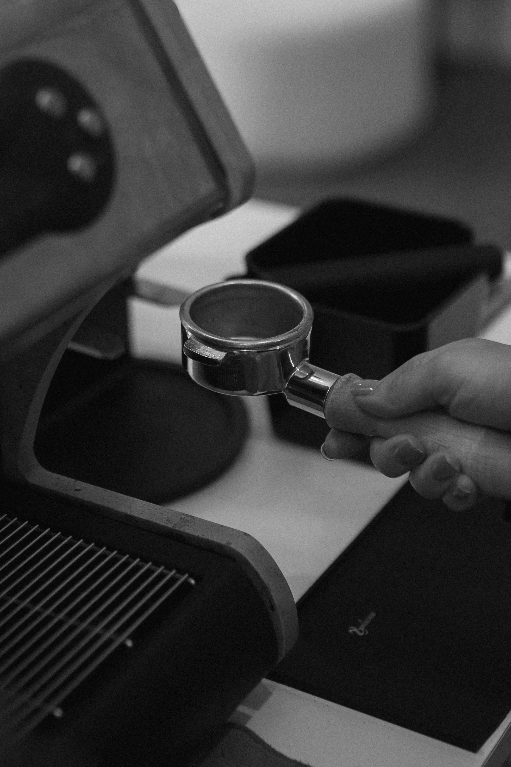 A person holding a portafilter of an espresso machine.