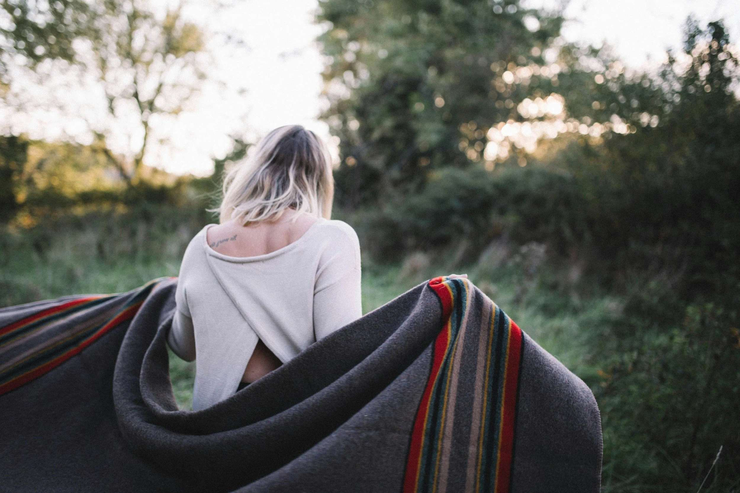 A guest relaxing with cozy blankets on the bow of a classic mahogany Hacker-Craft wooden boat during a fall color cruise.
