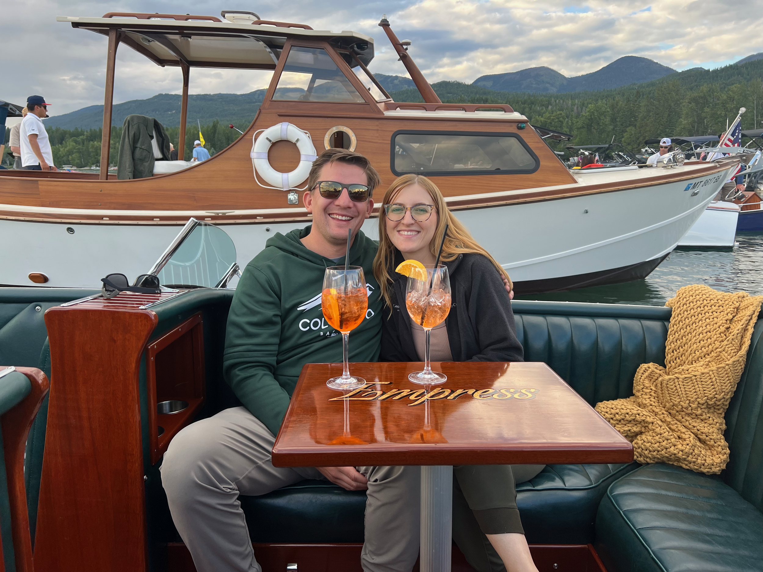 A romantic couple celebrating a luxury private boat engagement cruise, with Aperol Spritz, on Whitefish Lake, Montana,