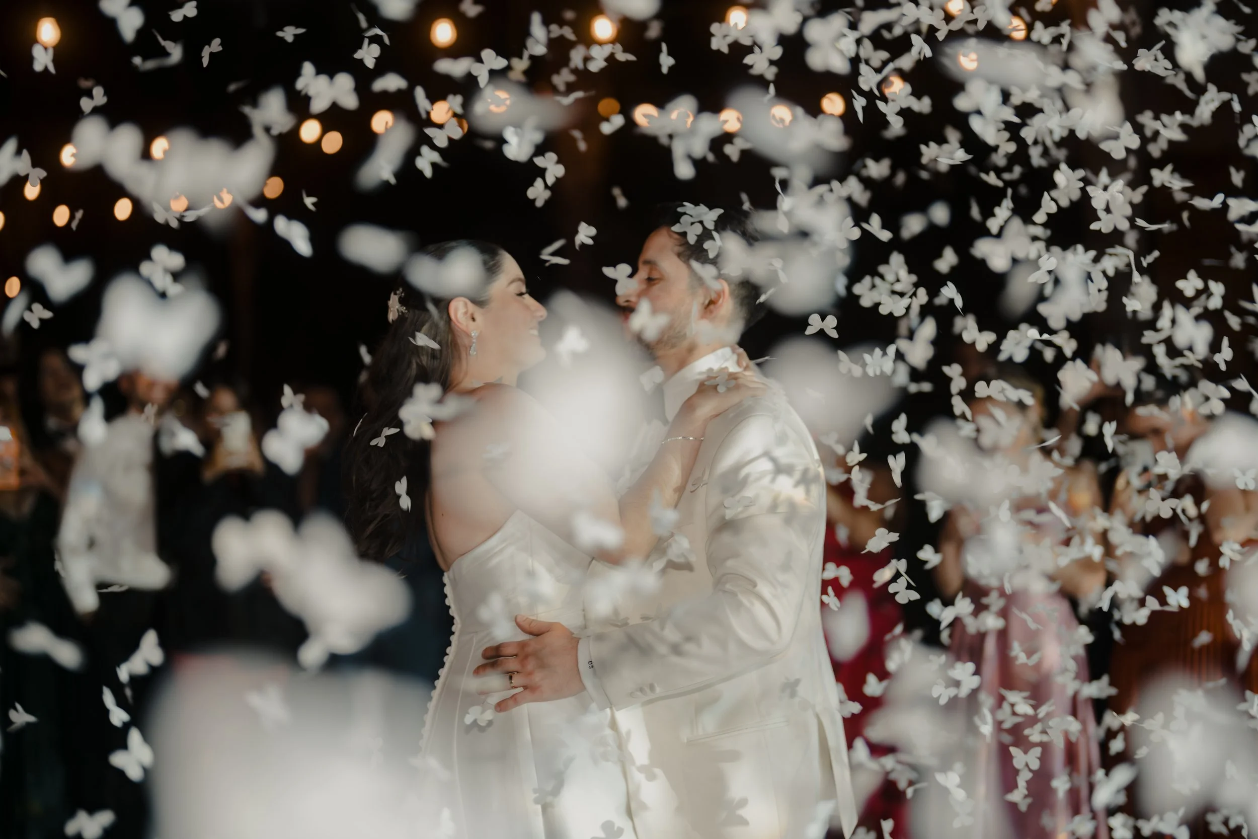 Pareja de recién casados bailando entre mariposas de papel en una celebración de boda.
