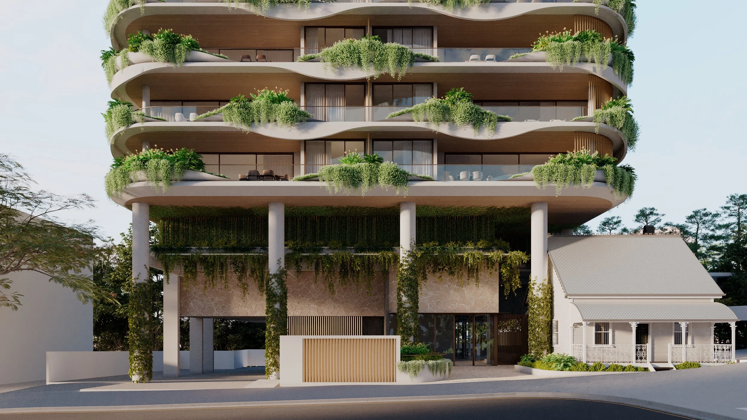 A modern multi-story building with curving balconies and abundant greenery on each level, supported by white columns, with trees and a small traditional house nearby.