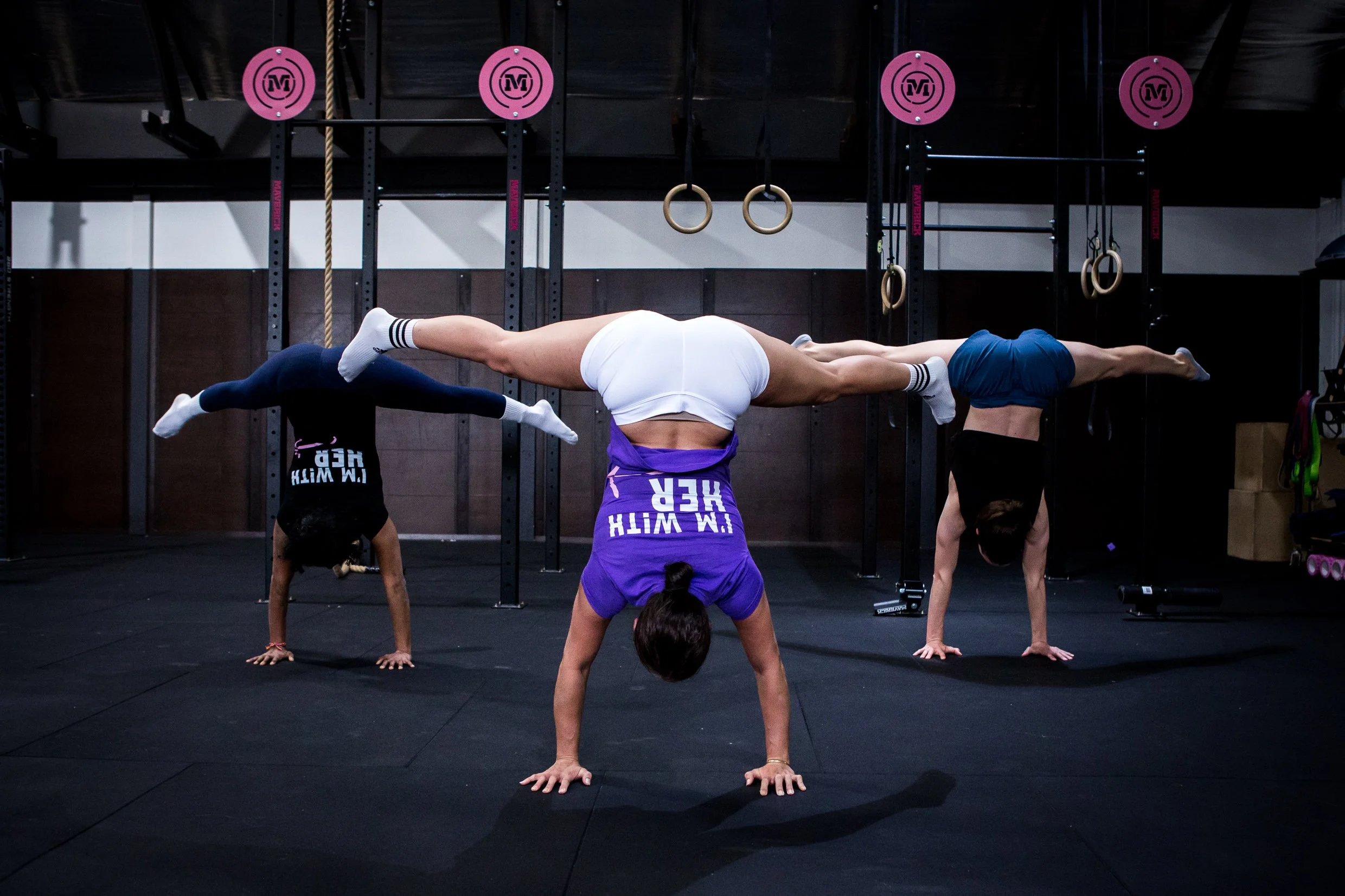three women doing straddle handstands