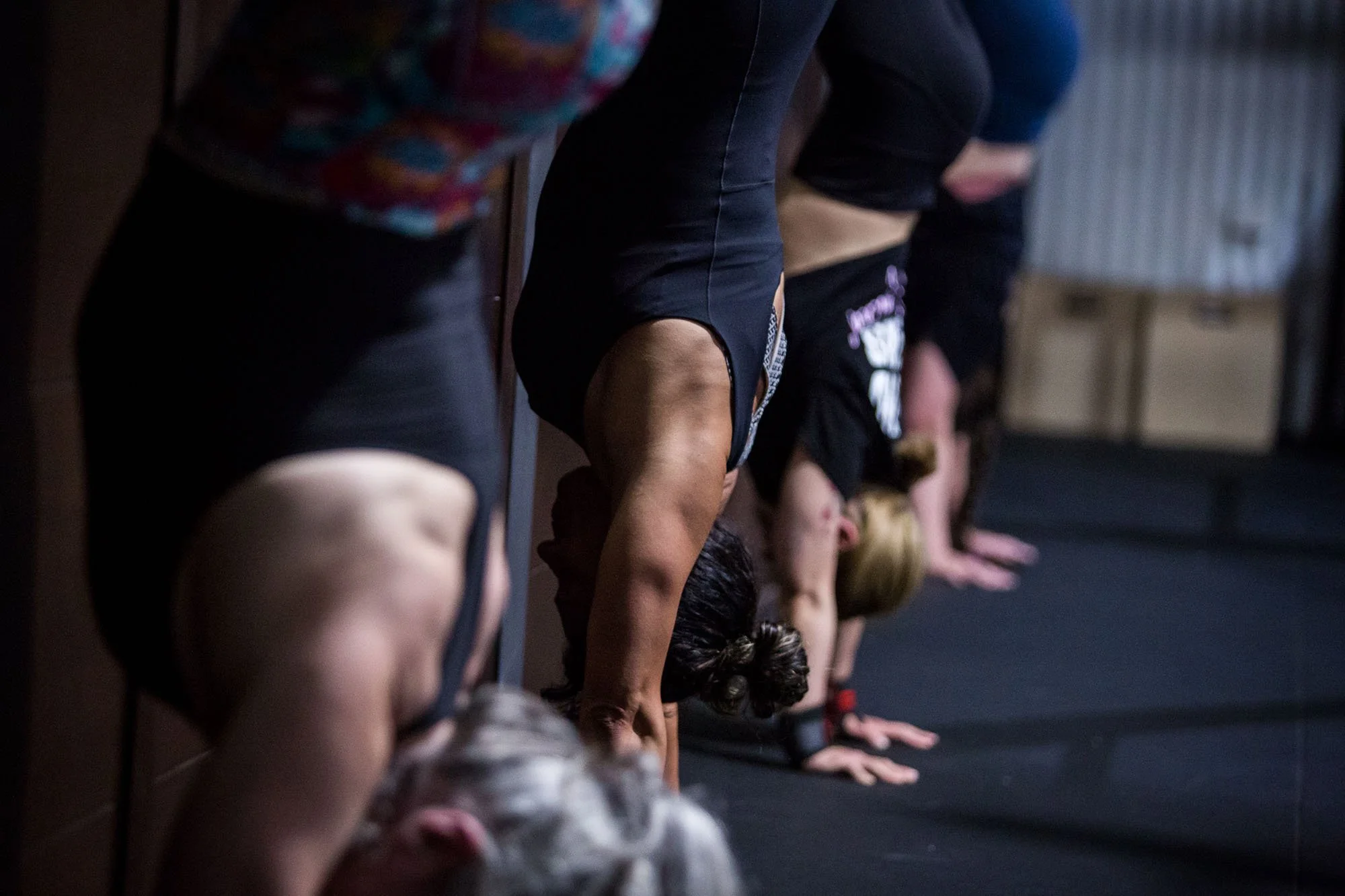 shoulders of four women doing handstands in a line