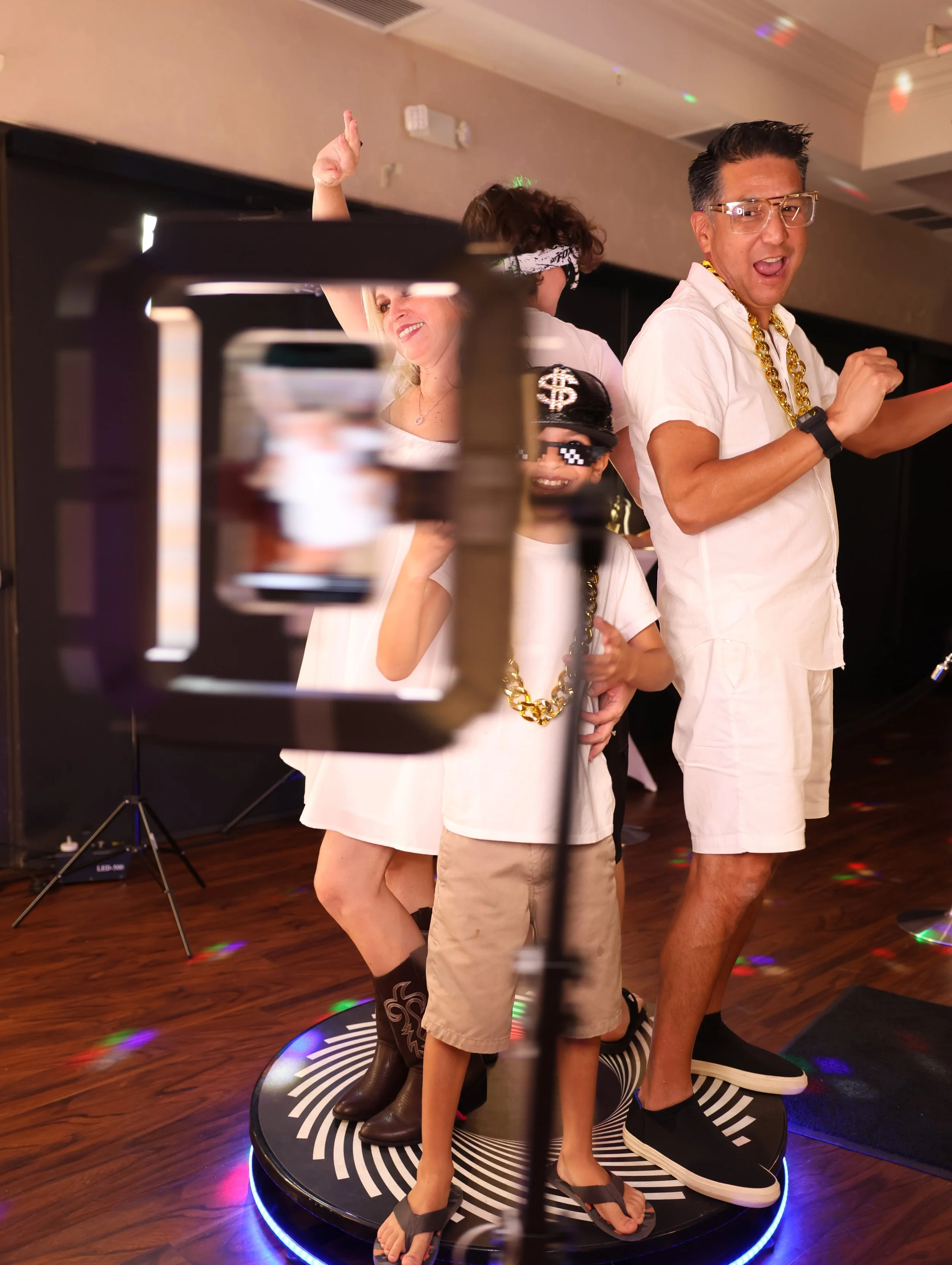 Group of people dancing on a revolving dance floor at a party, with disco lights and a dark background.