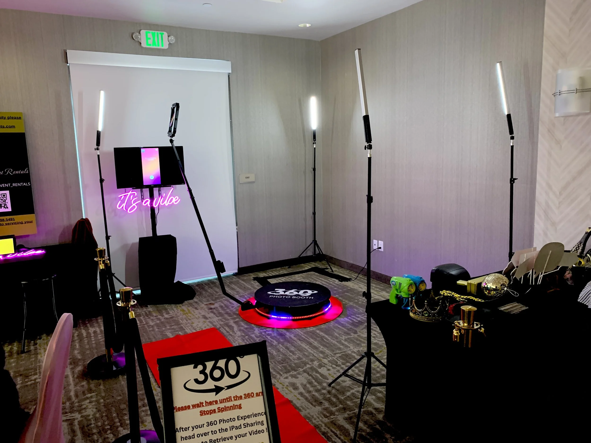 A photo booth setup at an event, including lighting, a monitor, and a sign with instructions for using the 360° photo booth.