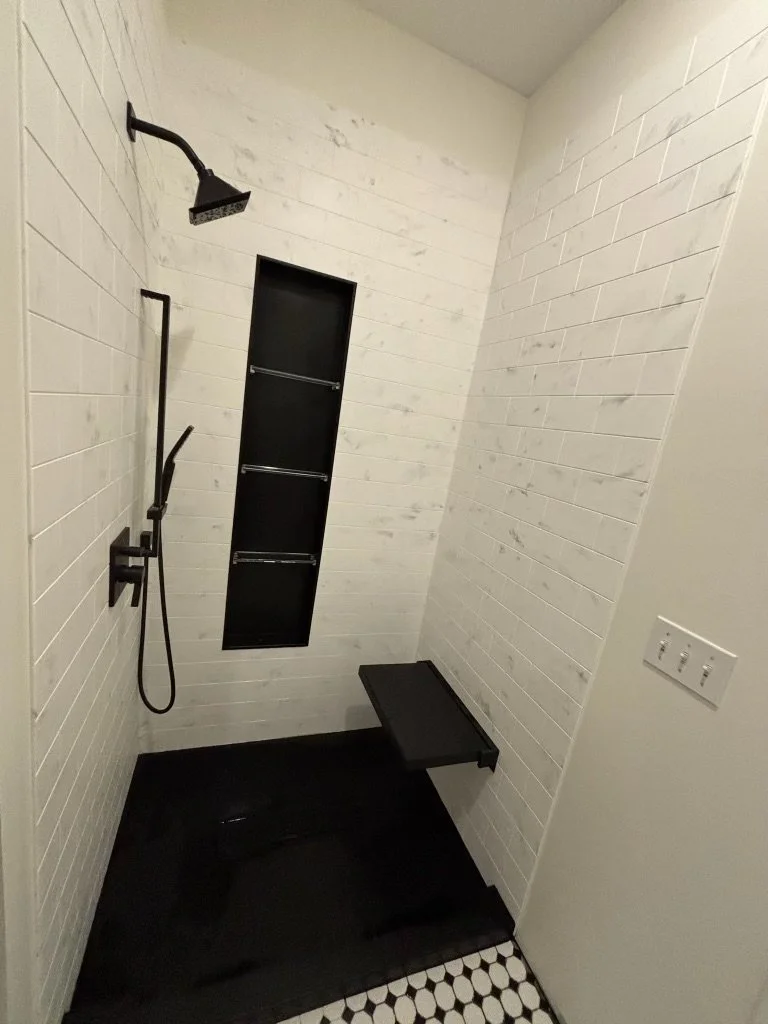 black-fixture-shower-marble-walls-niche-bench-checkered-floor-cortland-ohio.jpg