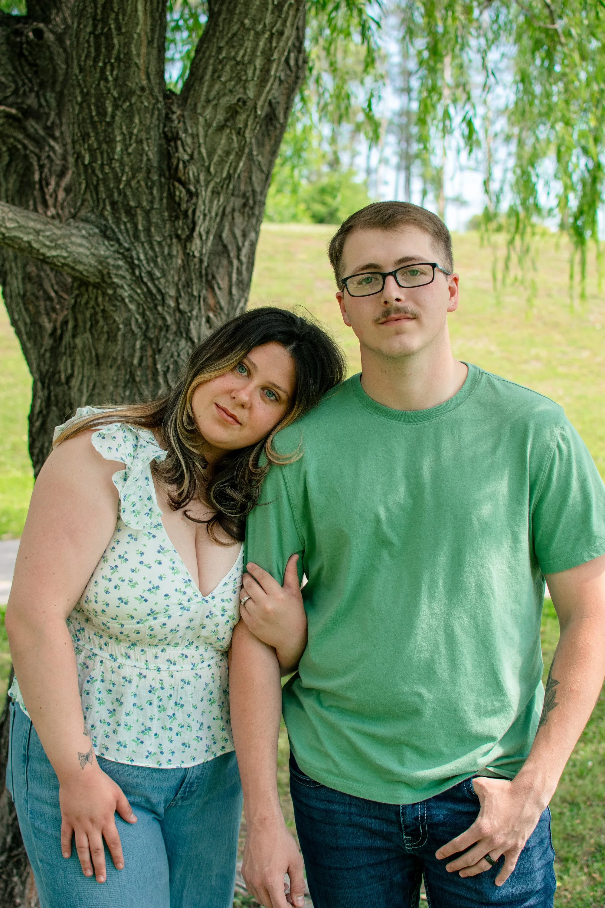 Young family posing together under a willow tree during a family portrait session