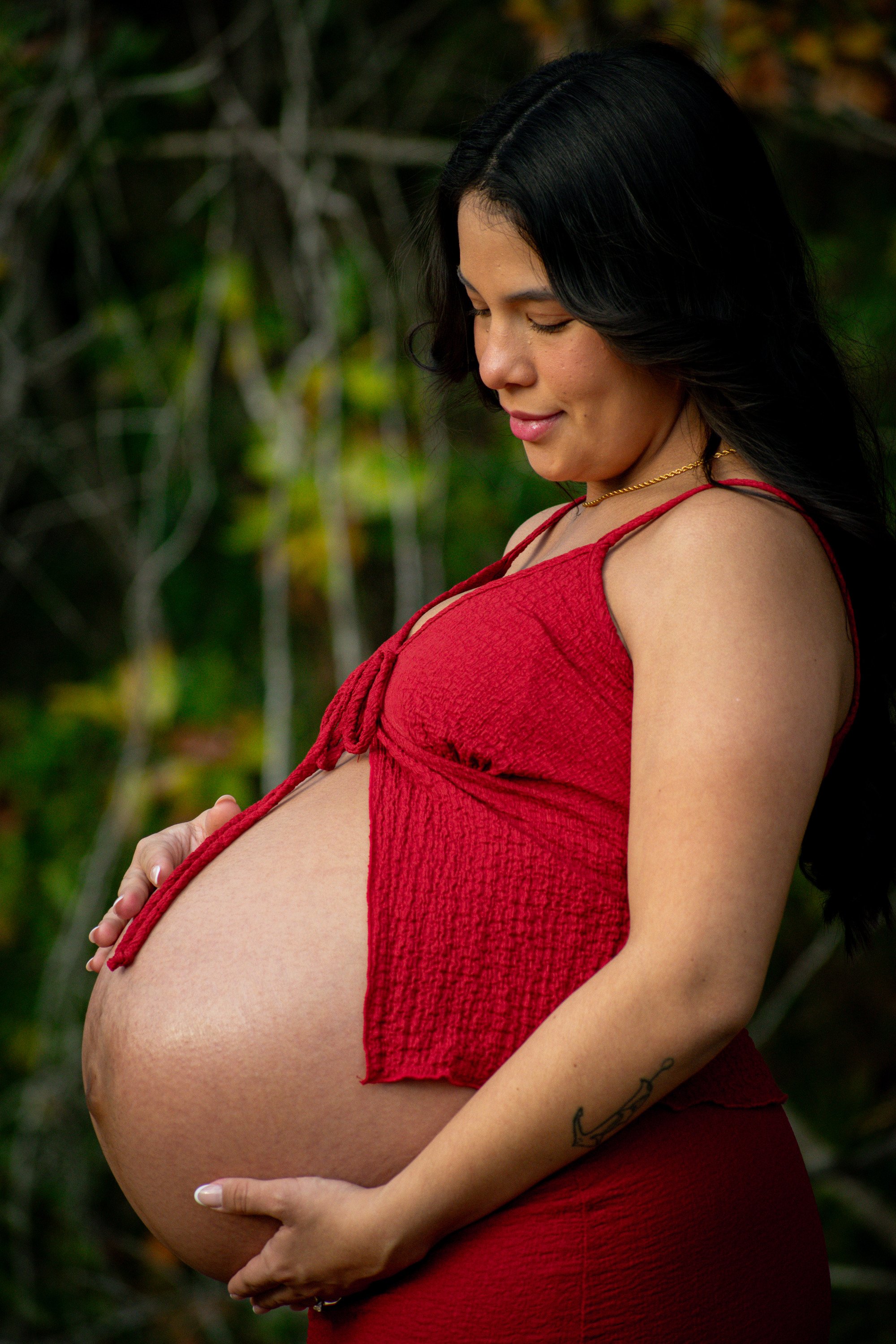 Expecting mother wearing a red dress during an outdoor maternity photography session