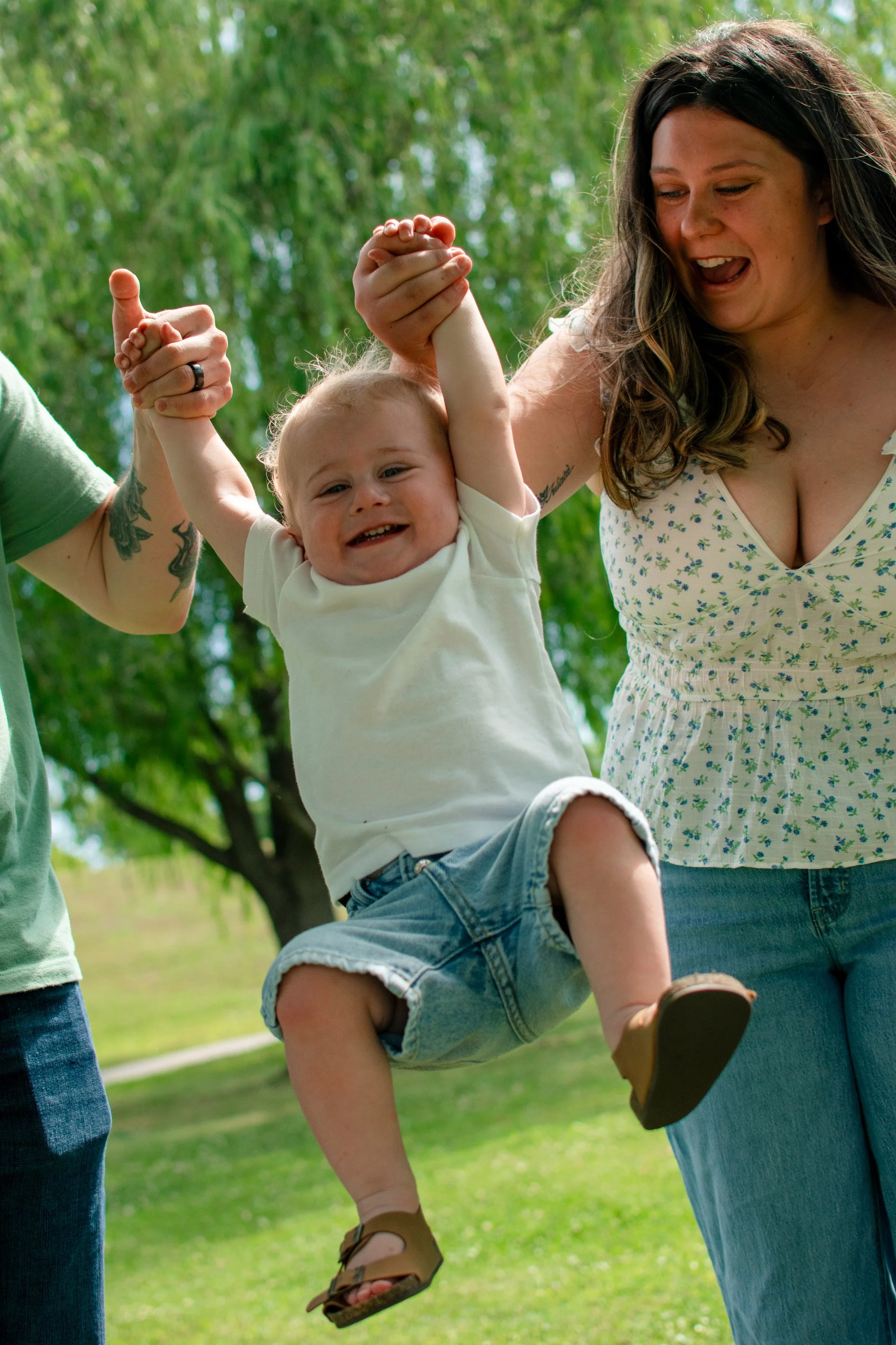 Smiling toddler being lifted by parents during an outdoor family photography session