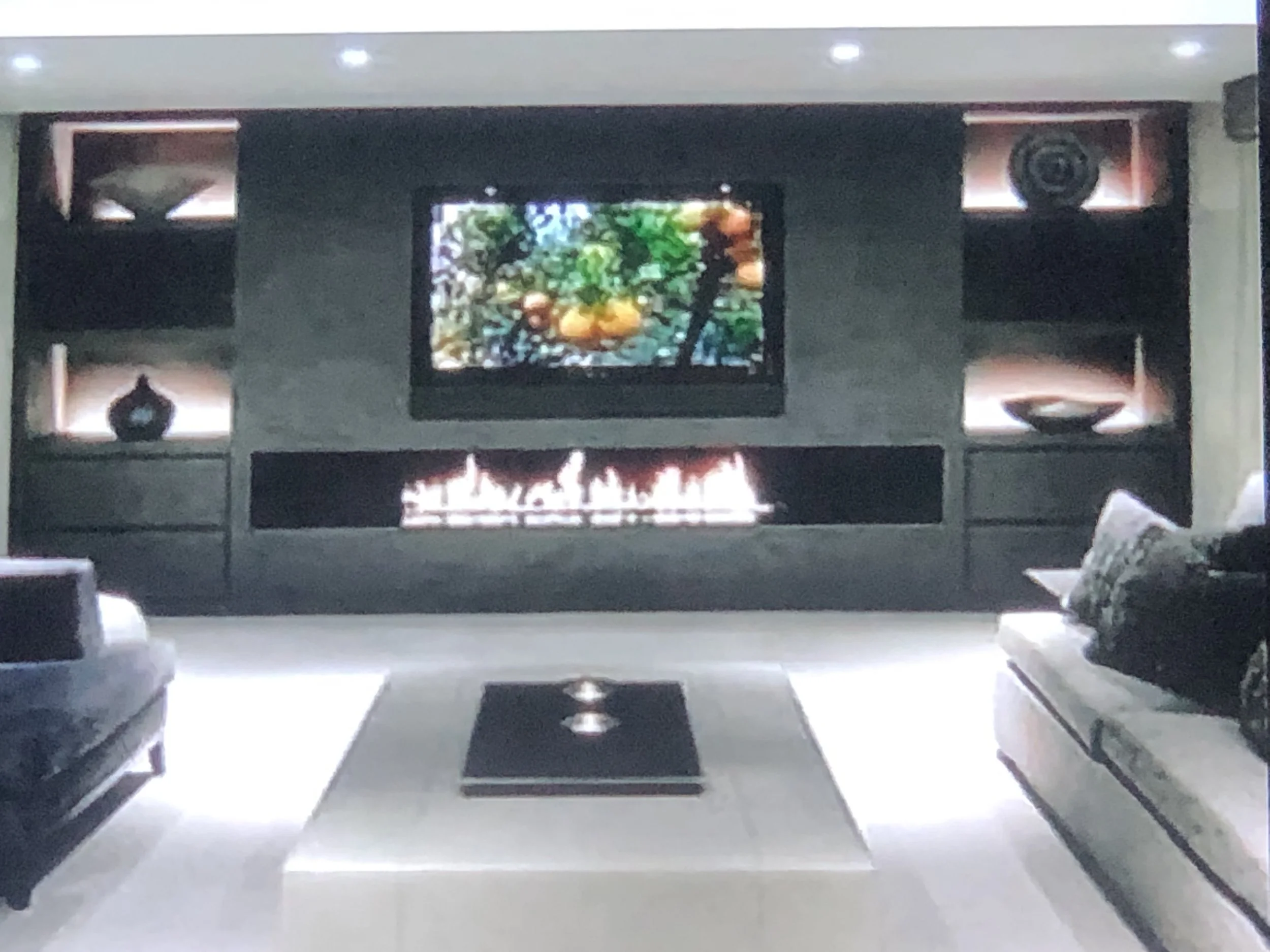 Modern living room with fireplace, flat-screen TV, and artwork on the walls, featuring sleek furniture and contemporary decor.