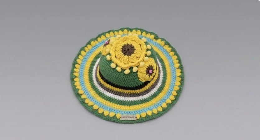 Colorful crochet hat with yellow flowers and a circular rainbow pattern.