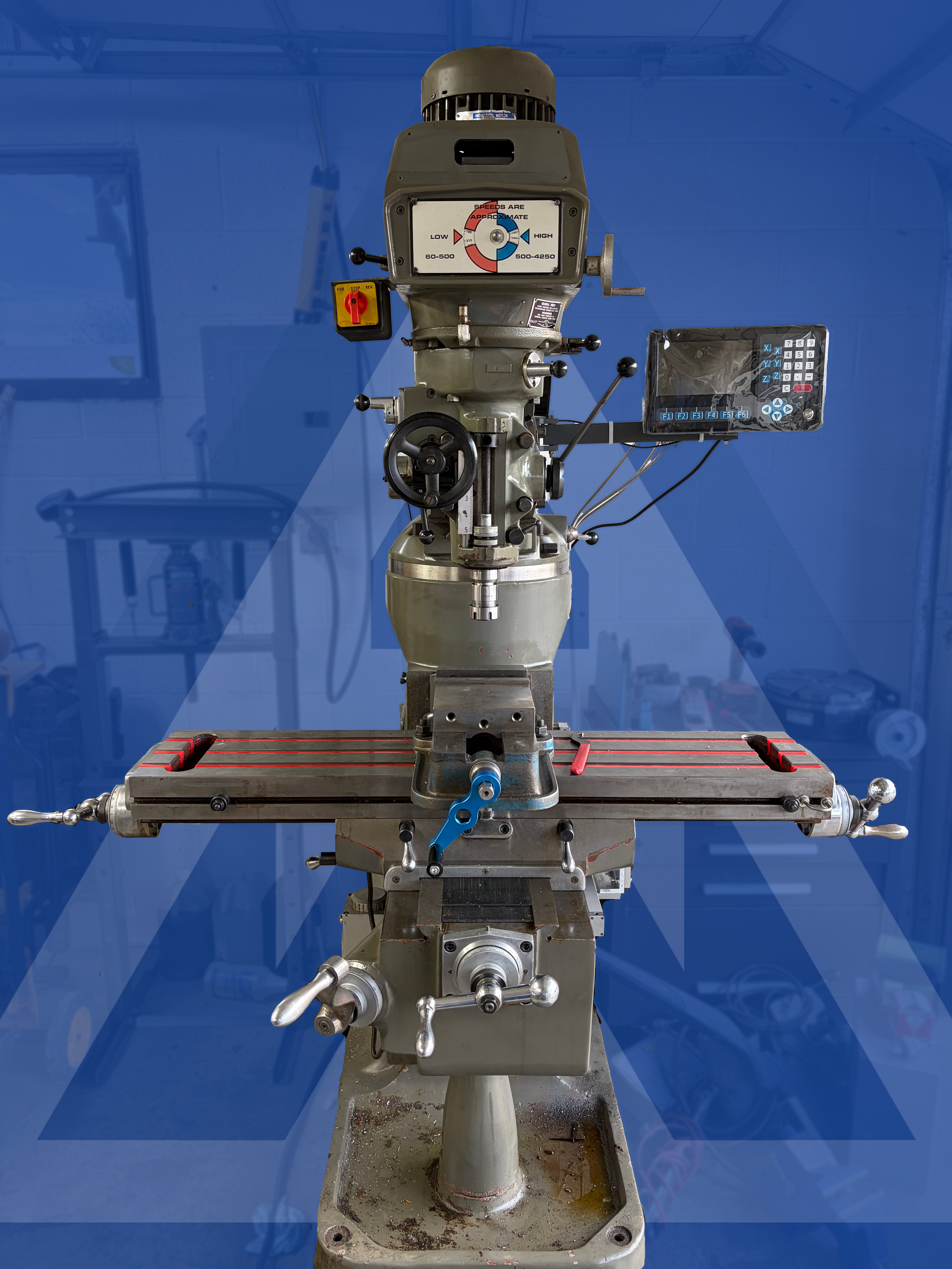 A vertical milling machine with a metal worktable and various controls, set against a blue background.