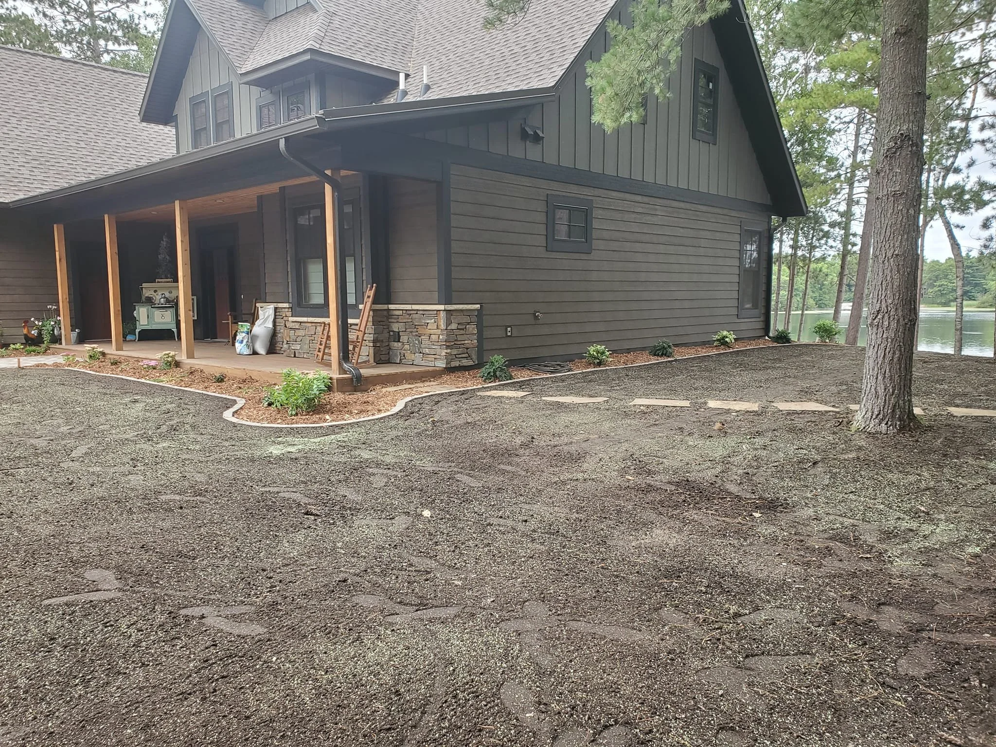 Residential backyard with a stone staircase, a gravel pathway, a propane tank labeled 'Lakes Gas,' and trees in the background.