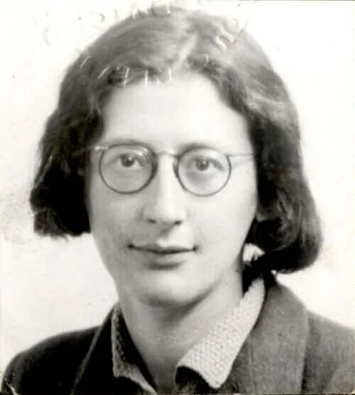 Black and white portrait of a woman with shoulder-length hair, glasses, and a suit jacket.