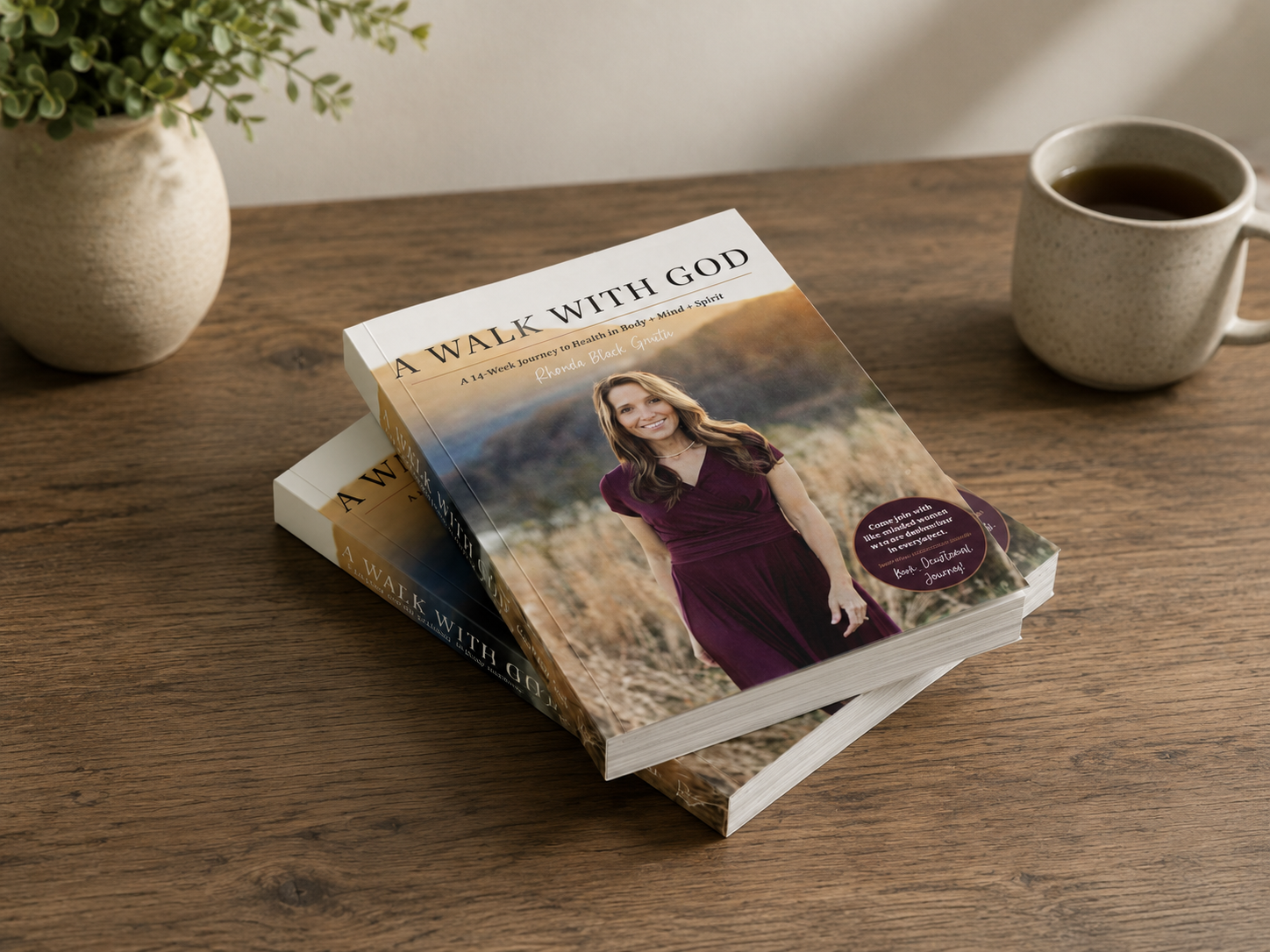 Two books titled "A Walk with God" placed on a wooden table, with a potted plant on the left and a mug of coffee on the right.