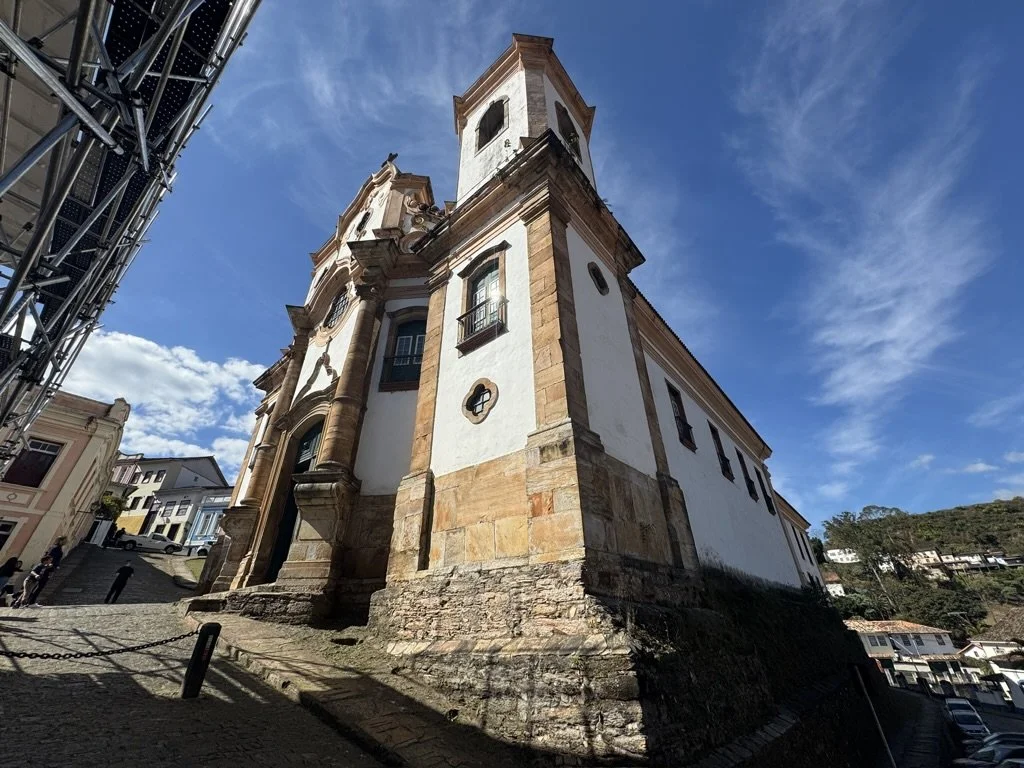 A historic church situated on a sloped street in a small town, with a clear blue sky overhead.