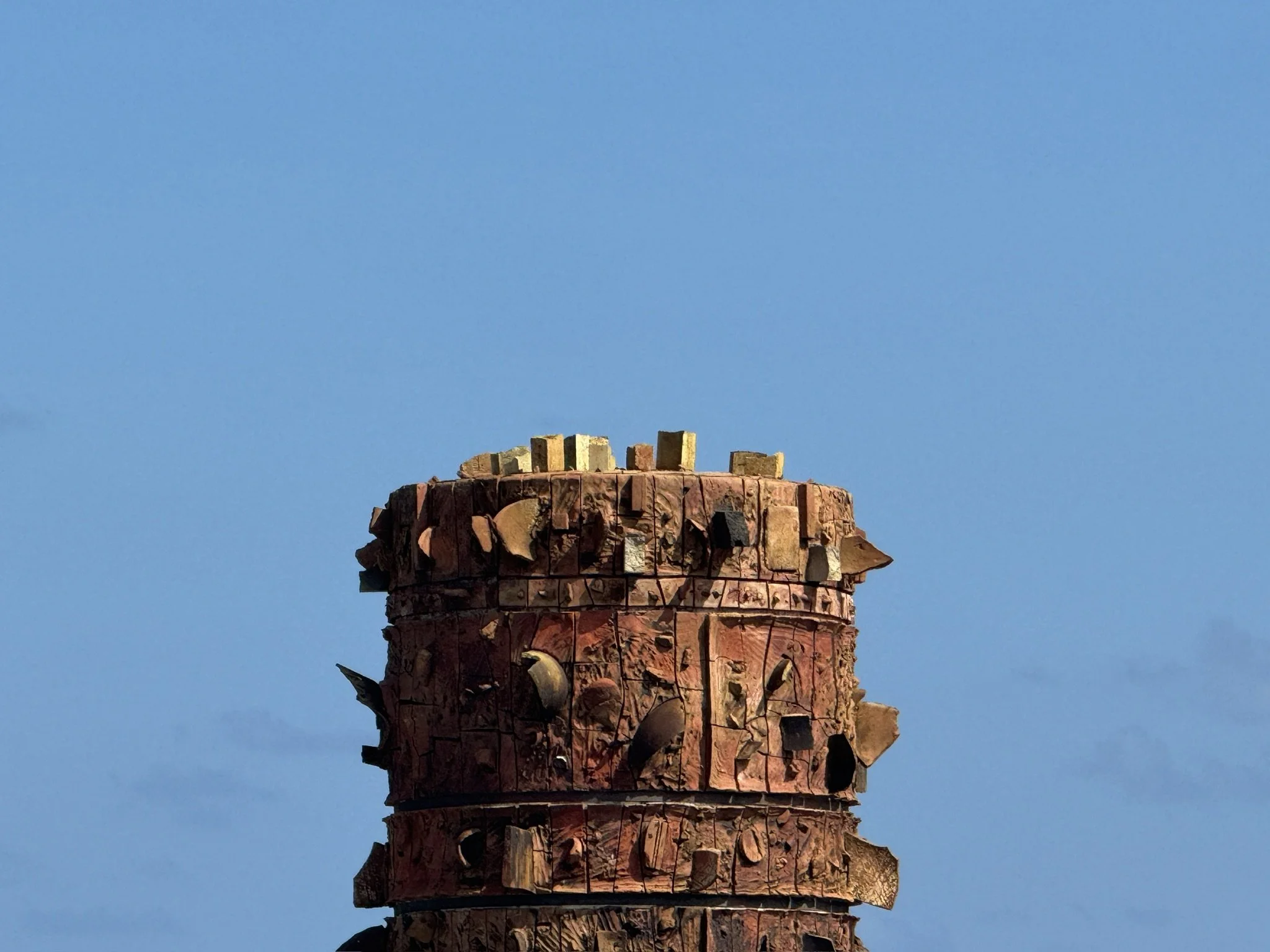 Close-up of a red brick chimney against a clear blue sky.